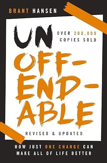 Book cover titled 'Unoffendable' by Brant Hansen, with the subtitle 'How Just One Change Can Make All of Life Better.' The cover features black, white, orange, and gray colors, with orange accents on the corners.