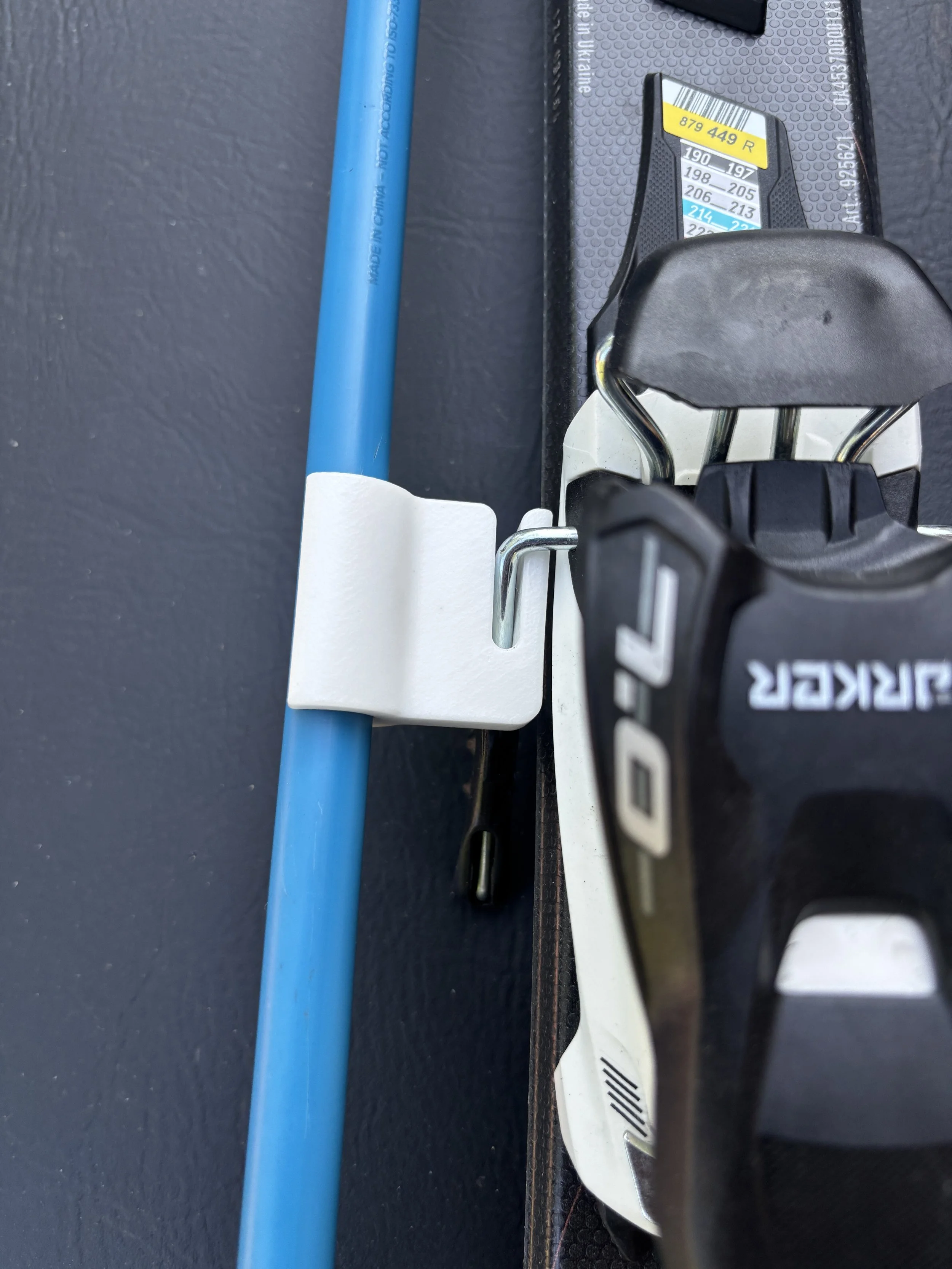 Close-up of a section of a gym weight lifting platform, showing a blue pipe, a black weight plate with a white label, and part of a weight lifting bar with branding.