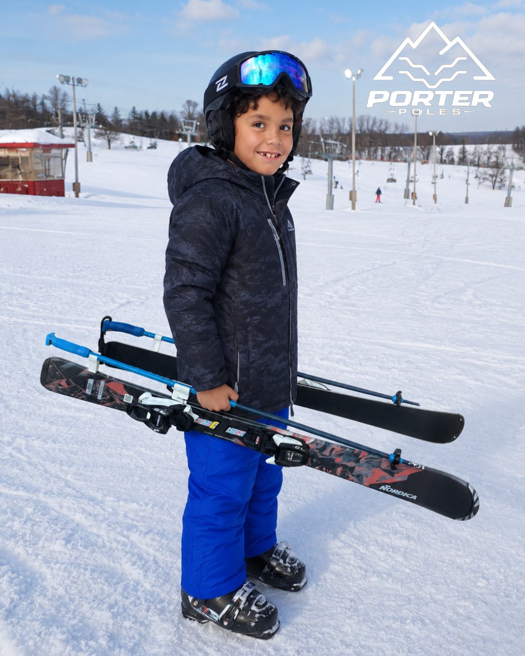 Young boy standing on snow with skis and ski poles at a ski resort, wearing a helmet and goggles, smiling, with ski lift and snow-covered trees in the background, and a Porter Poles logo in the top right corner.