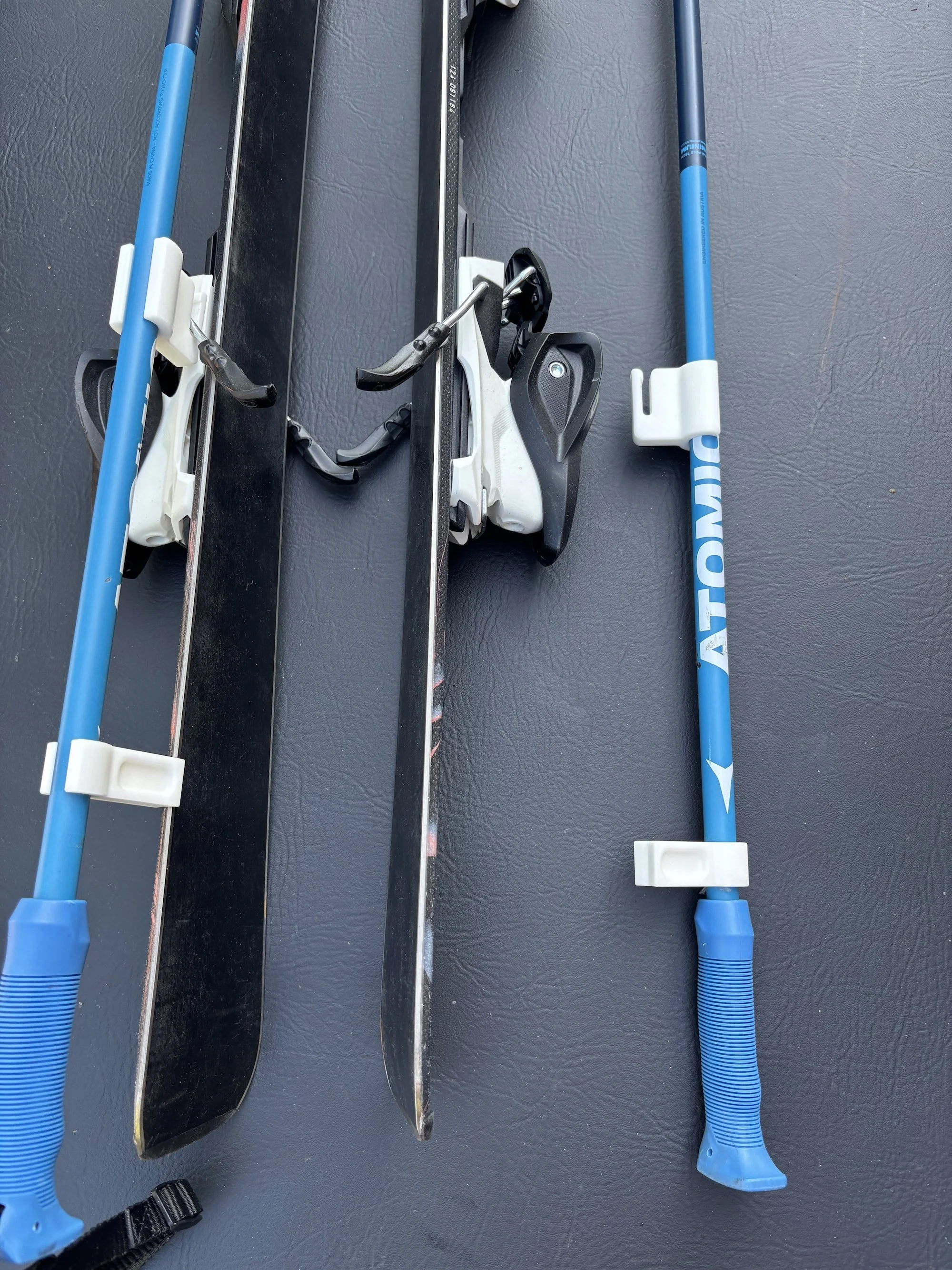 A pair of cross-country skis and ski poles placed on a black surface.