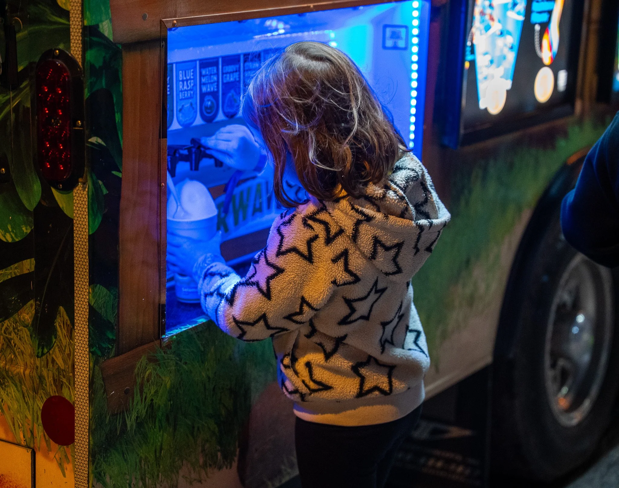 A young attendee adding flavor to shaved ice.