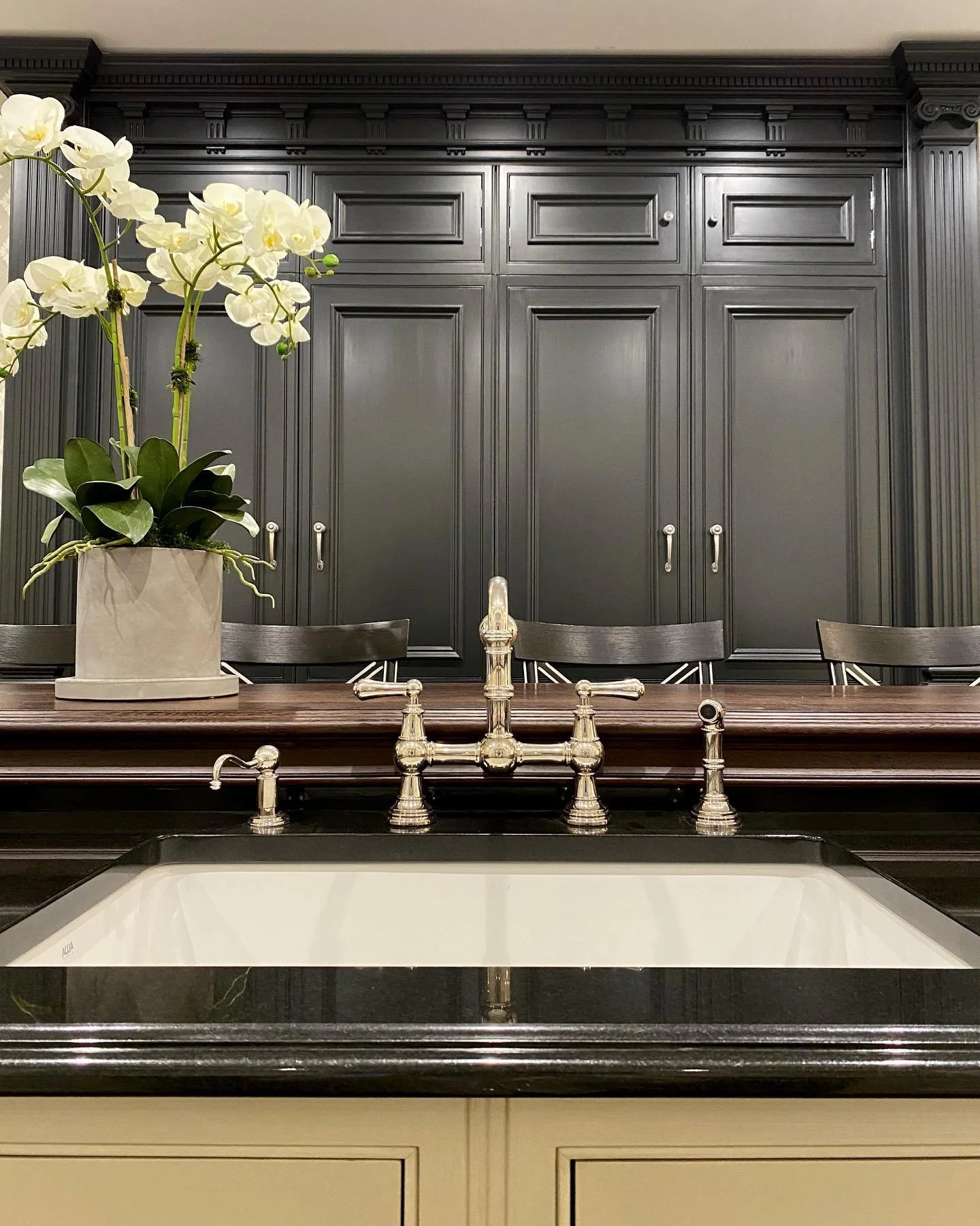 Polished nickel bridge faucet with black custom cabinetry and Wenge countertop.