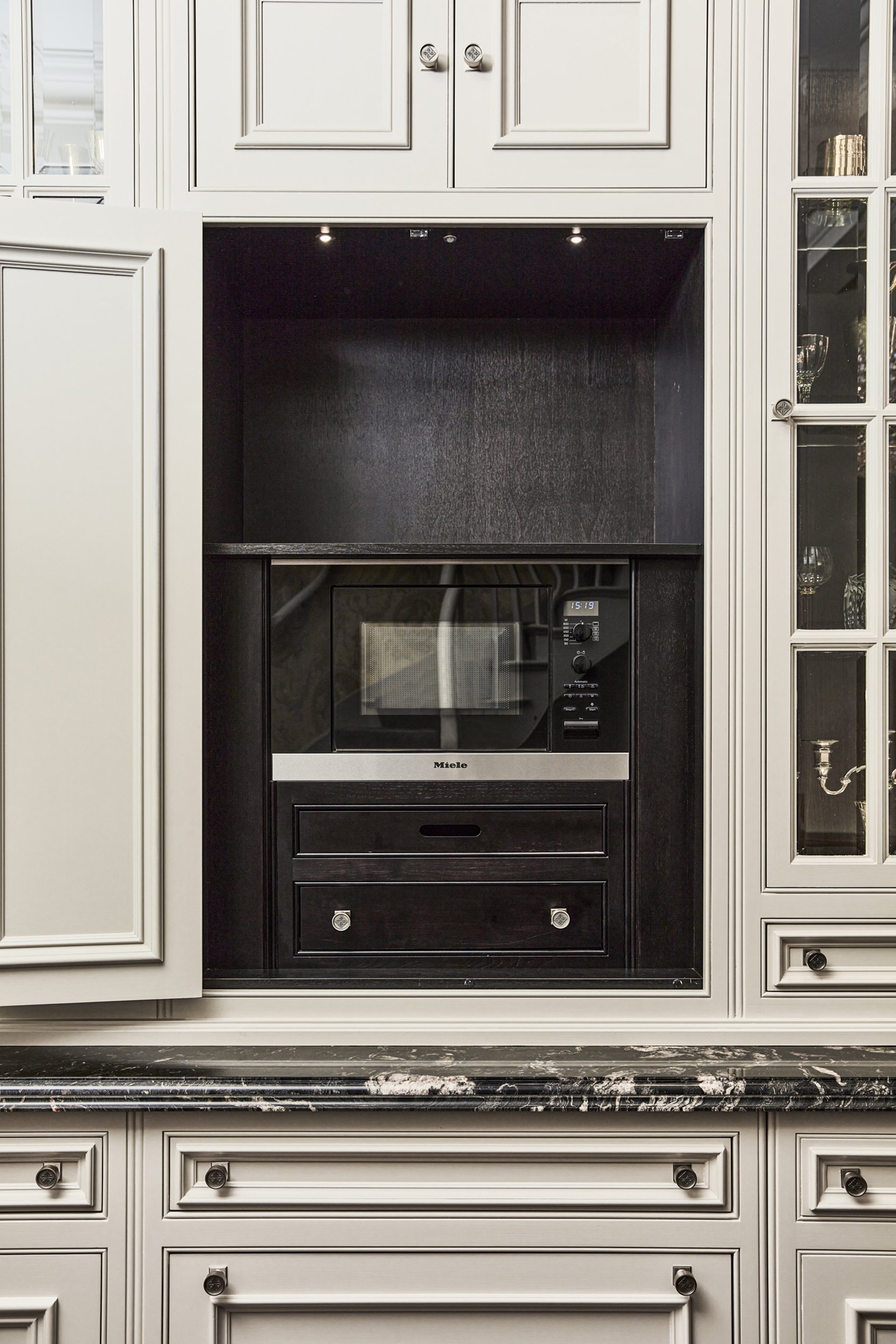 Clive Christian cabinetry detail with a built-in microwave and marble countertop.
