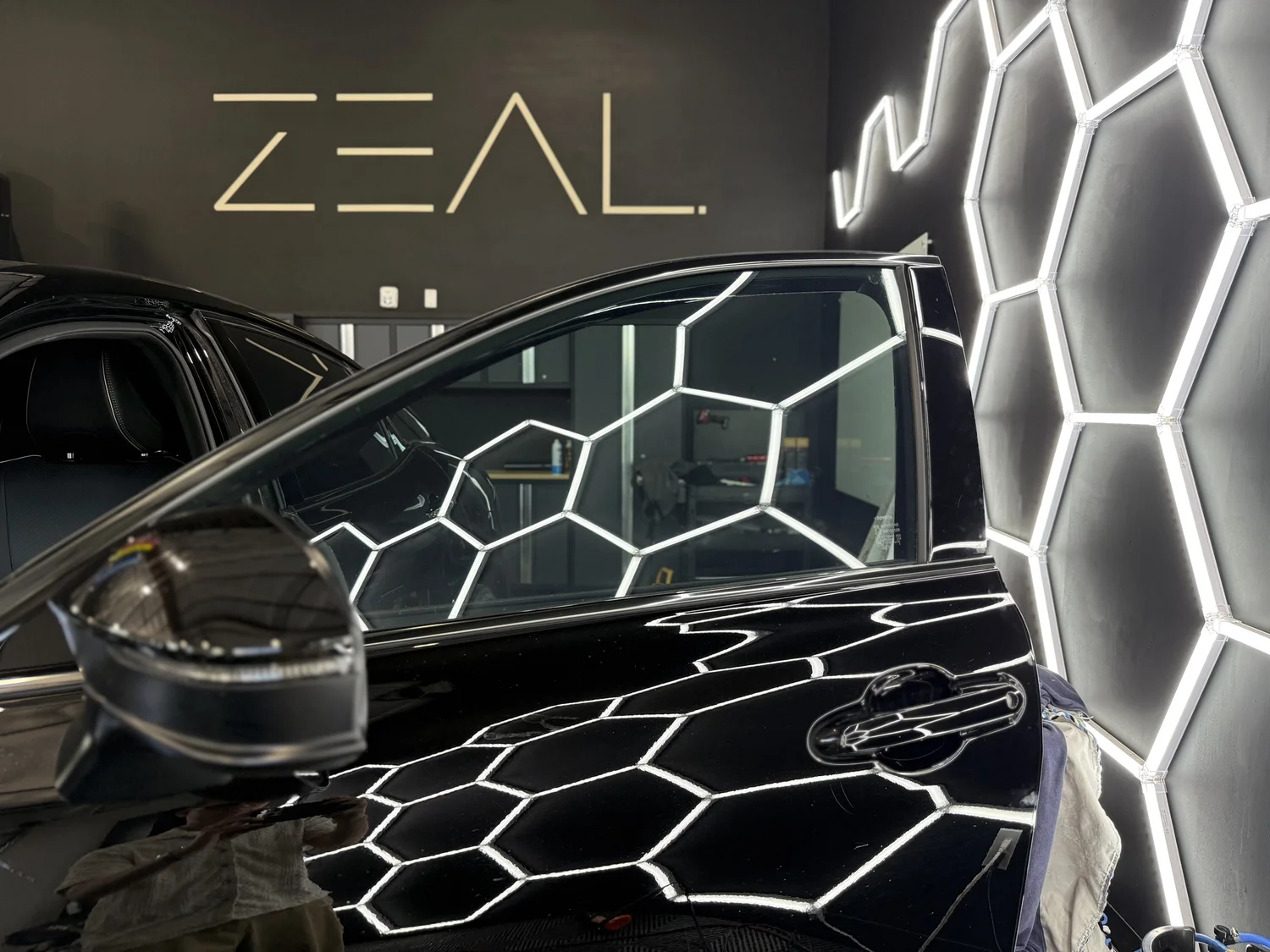 Black car under the hex lighting at Zeal Restyling after a Spectre NanoCeramic window tint install
