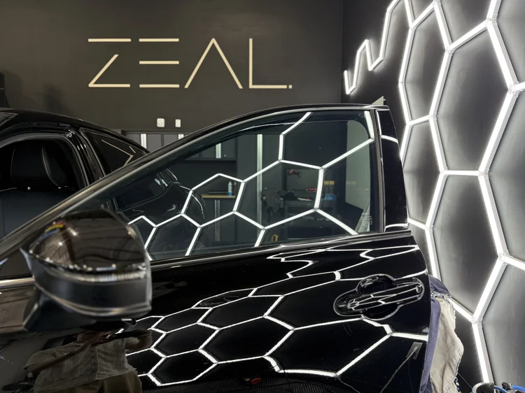 Black BMW under the hex lighting at Zeal Restyling after a Spectre NanoCeramic window tint install in Bluffdale, Utah