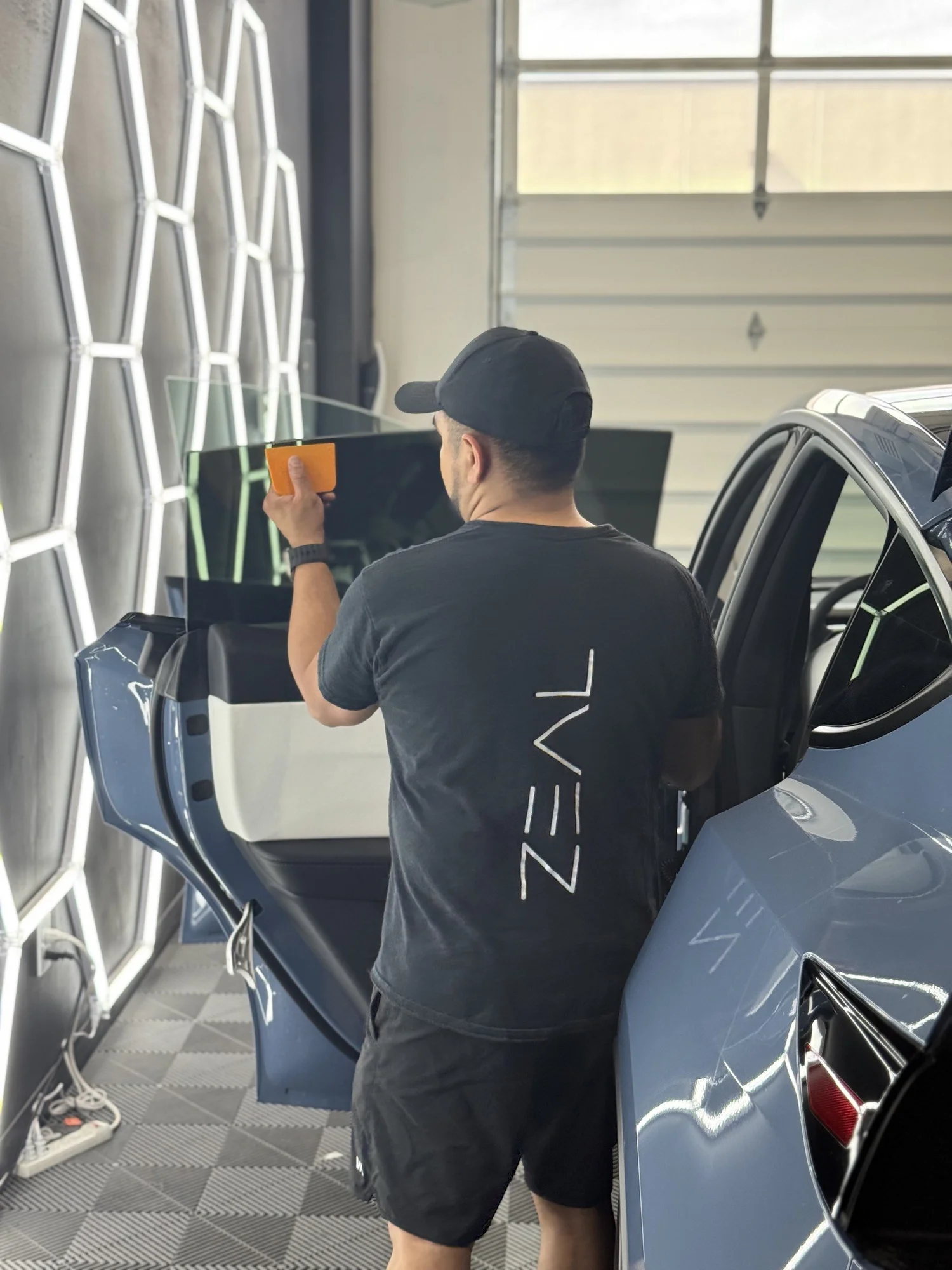 Lead technician applying premium ceramic tint film to a car window in Bluffdale, Utah