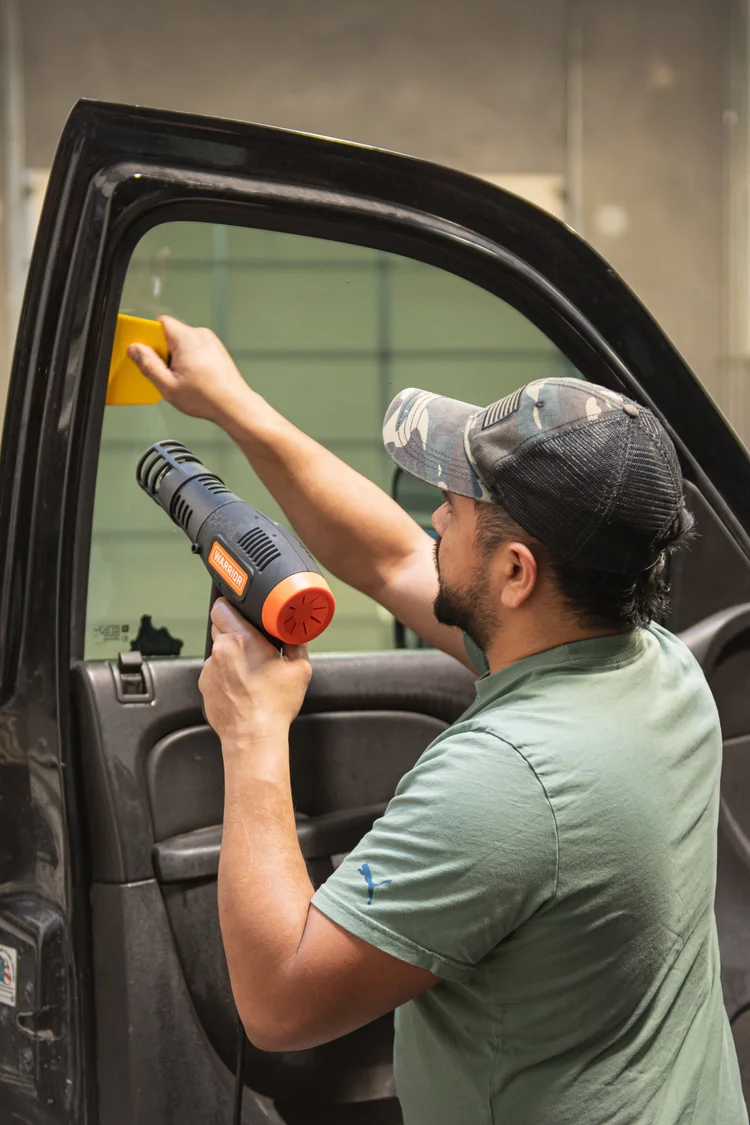 Zeal Restyling technician heat forming Shadow Hybrid Carbon tint film onto a truck window