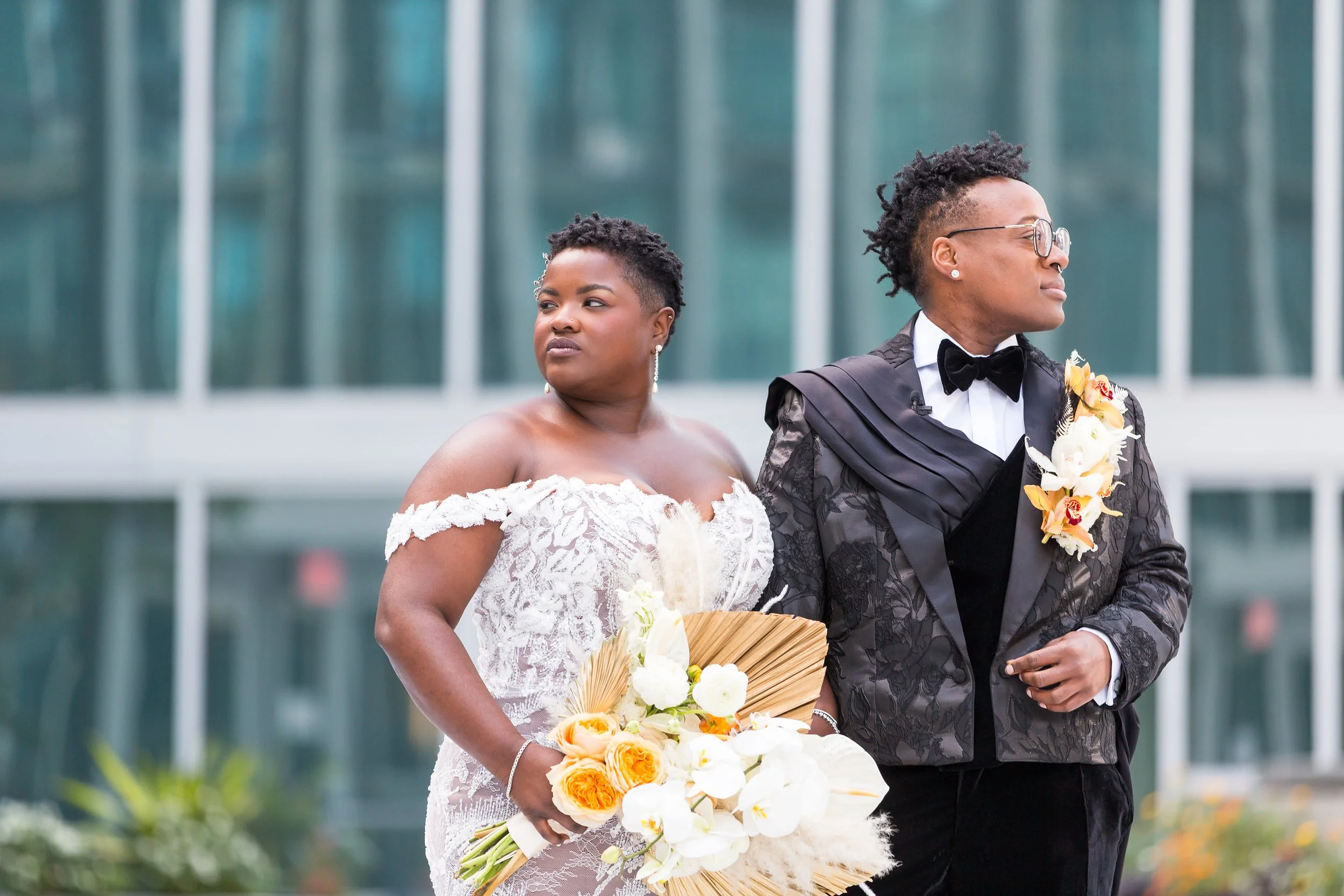 brides in white gown and black suit with large custom bouquet and extra large boutonniere in white cream and rust