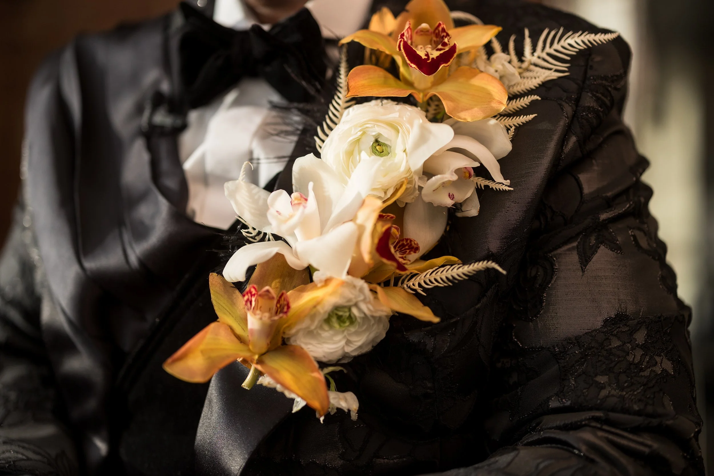 close up of extra large premium boutonniere featuring white and orange cymbidium orchids