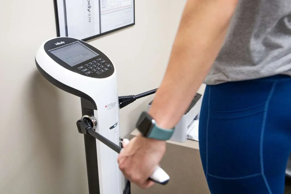 Person using a fitness device or health monitor in a clinical or gym setting.