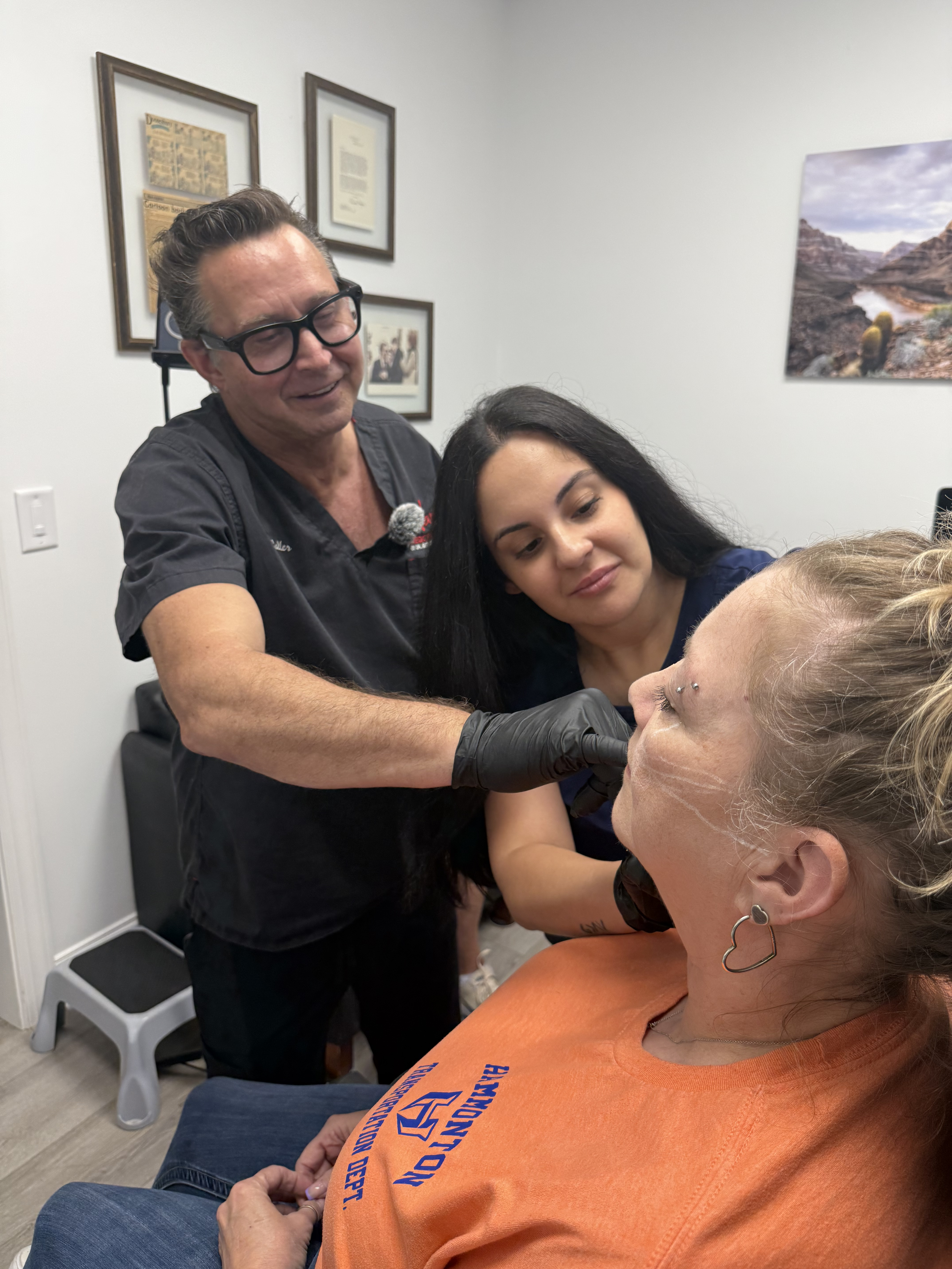 A woman receiving a cosmetic consultation from a healthcare professional while another woman observe.