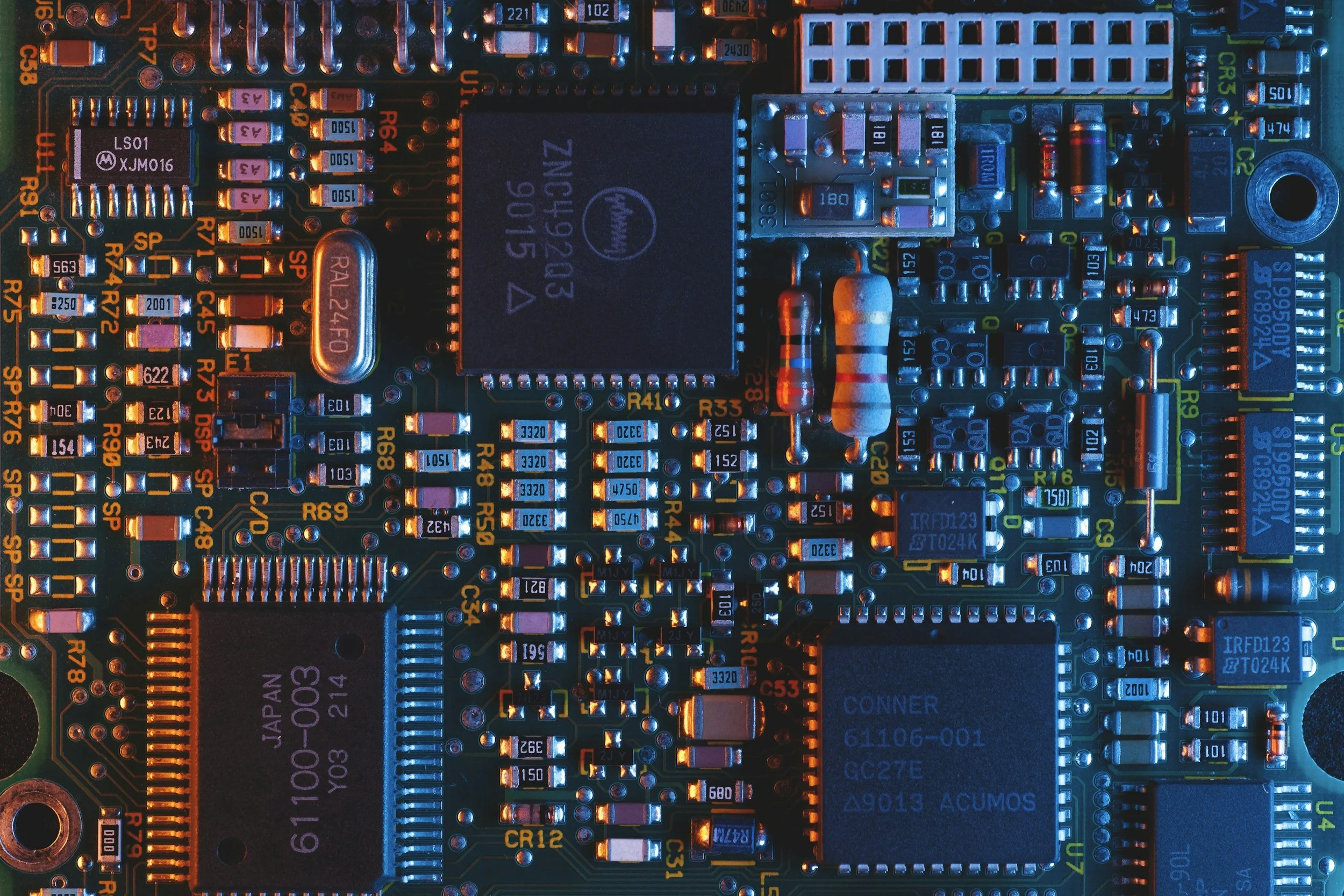 Close-up of a computer circuit board with various electronic components and colored wiring.