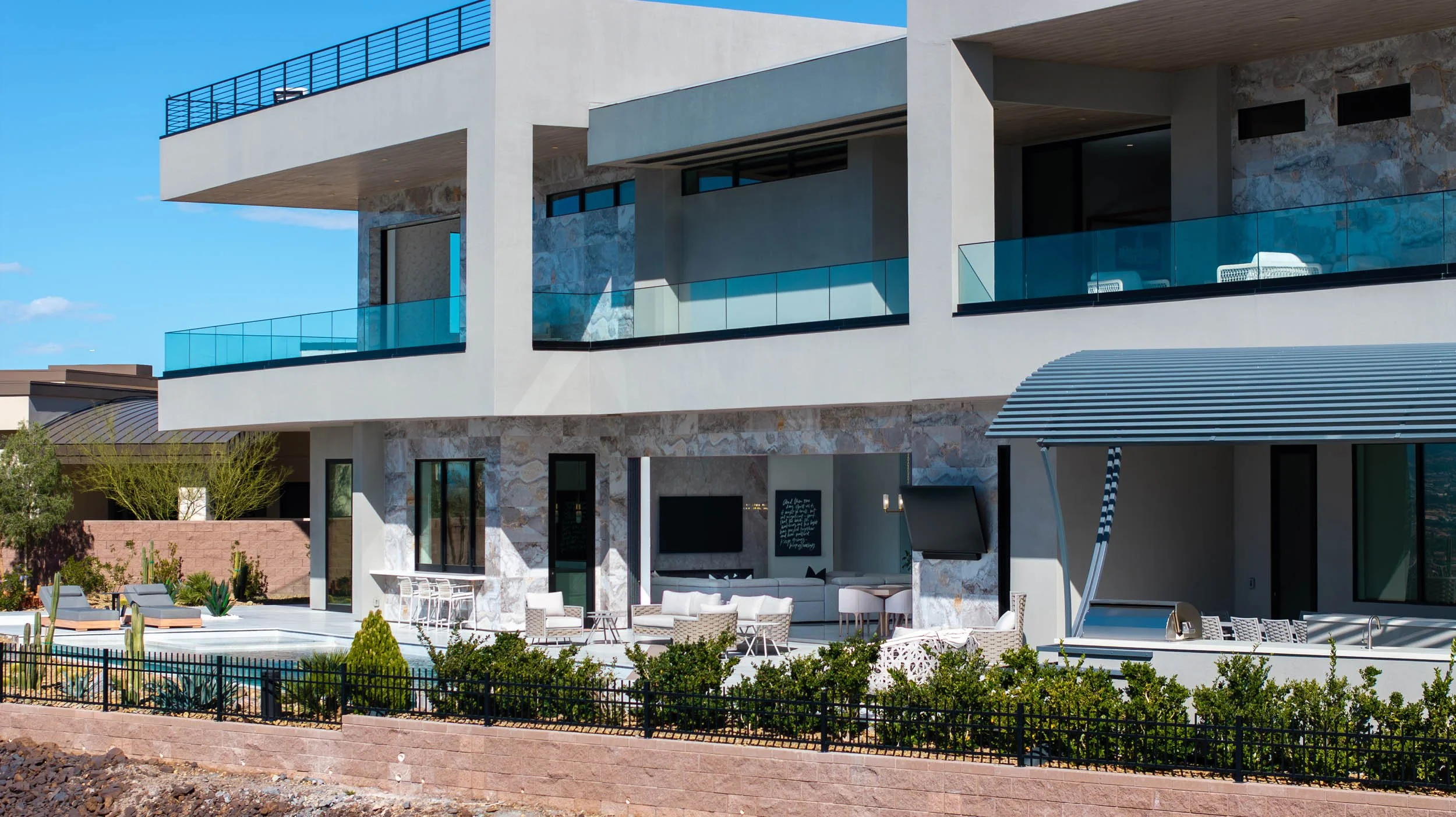 Modern multi-story house with balconies, outdoor seating area, pool, and landscaped yard.