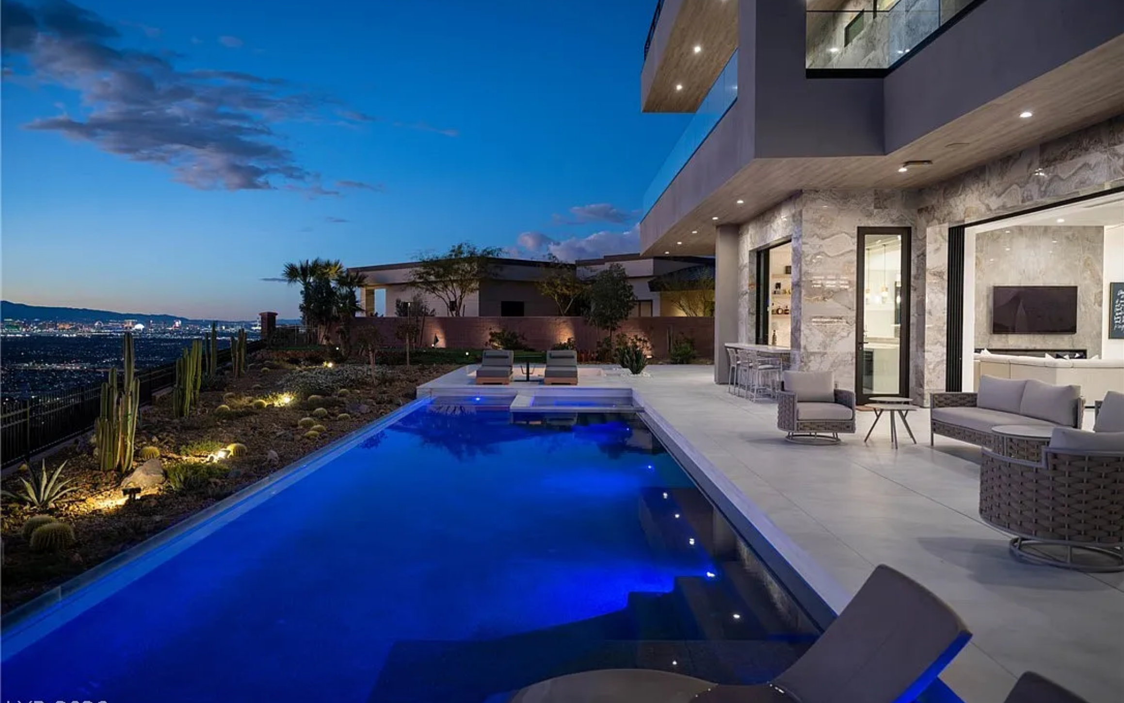 Luxury modern house with an outdoor pool, patio seating, and city view at dusk.