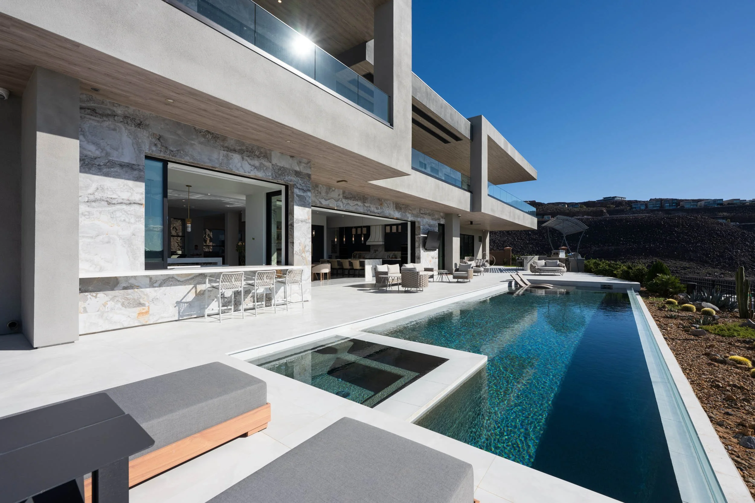 Modern house with outdoor pool and patio furniture under clear blue sky.