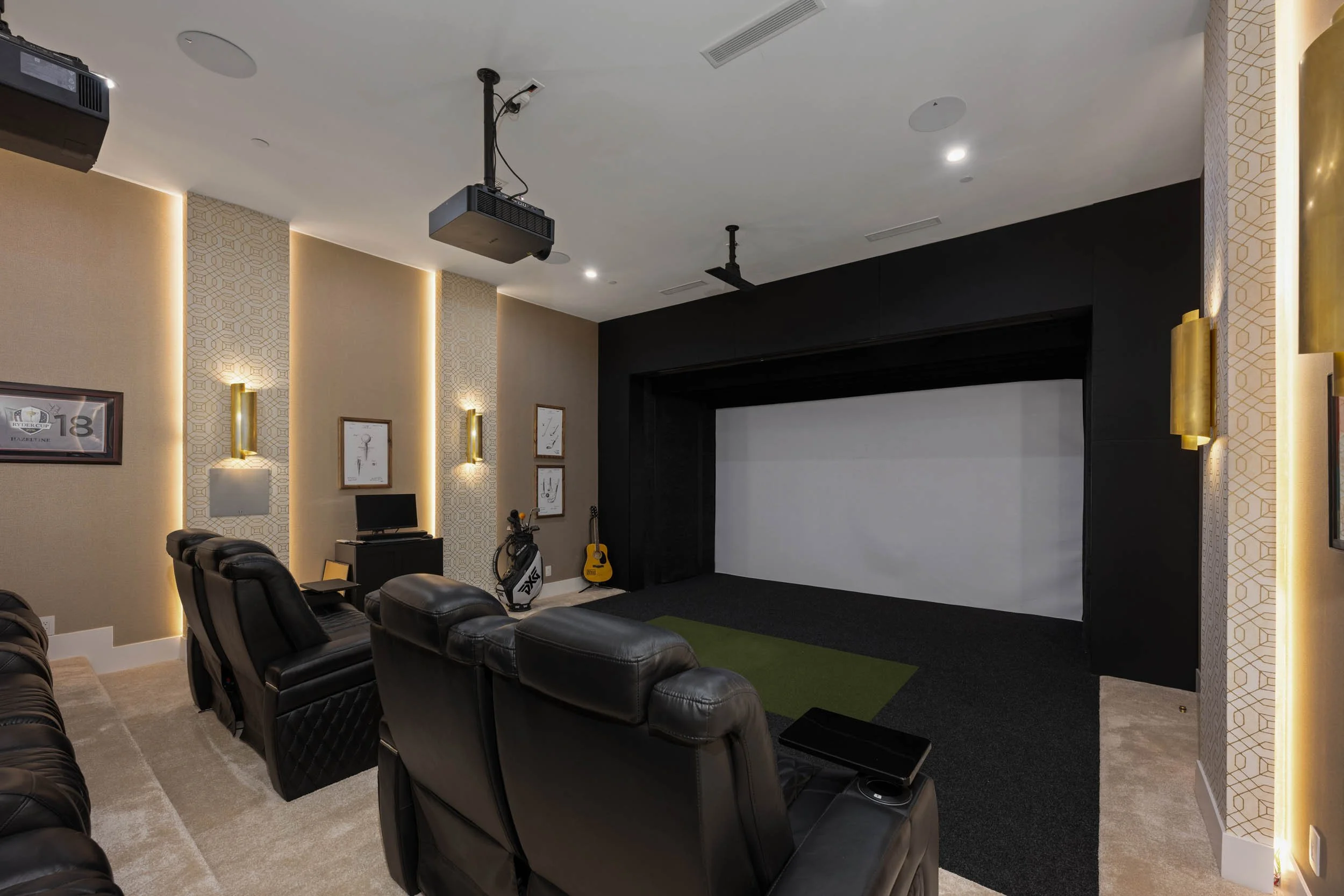Luxury home theater with black leather reclining chairs, a large screen, a projector, golf clubs, a yoga mat, and a guitar.