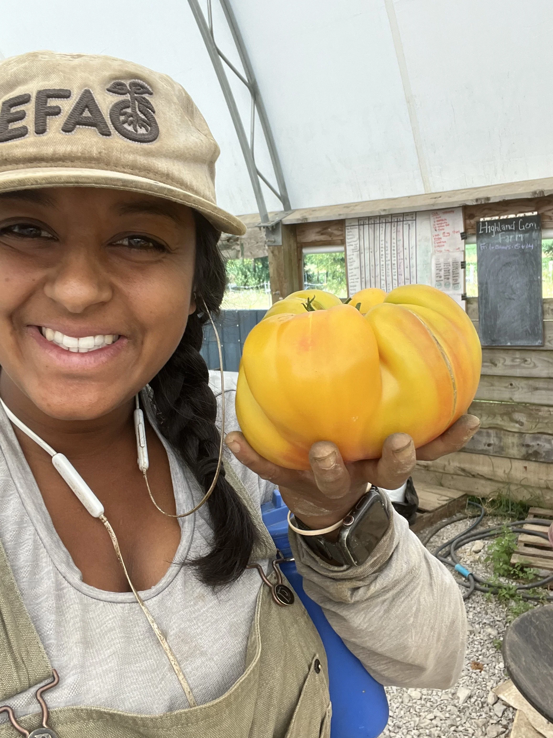 Isabelle owner of Vintage Soil Farm is smiling while holding a certified organic tomato