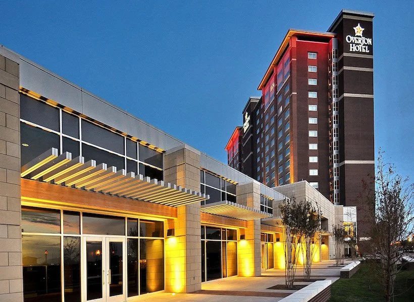 Exterior view of the Overton Hotel at dusk with lit windows and trees in front