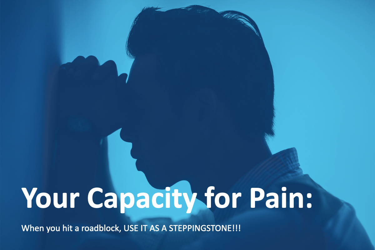 Silhouette of a man with his head resting against a wall, appearing stressed or contemplative, against a blue lit background. Text overlay reads: "Your Capacity for Pain: When you hit a roadblock, USE IT AS A STEPPINGSTONE!!!"