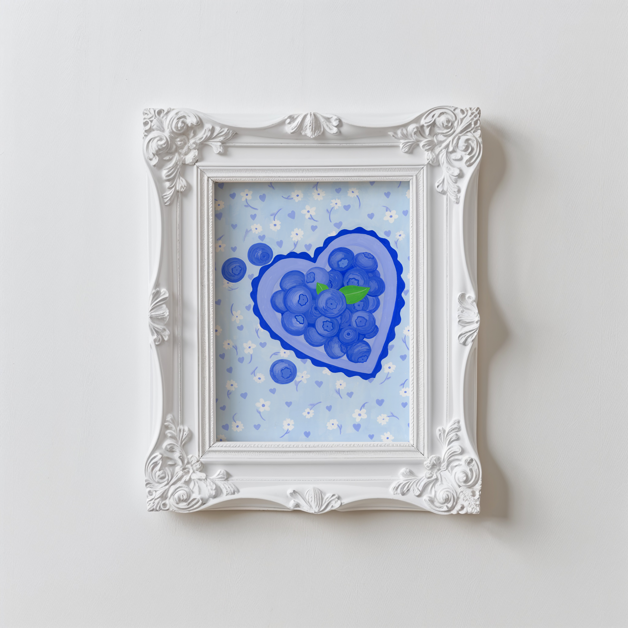 A framed painting of blueberries in a white vintage frame