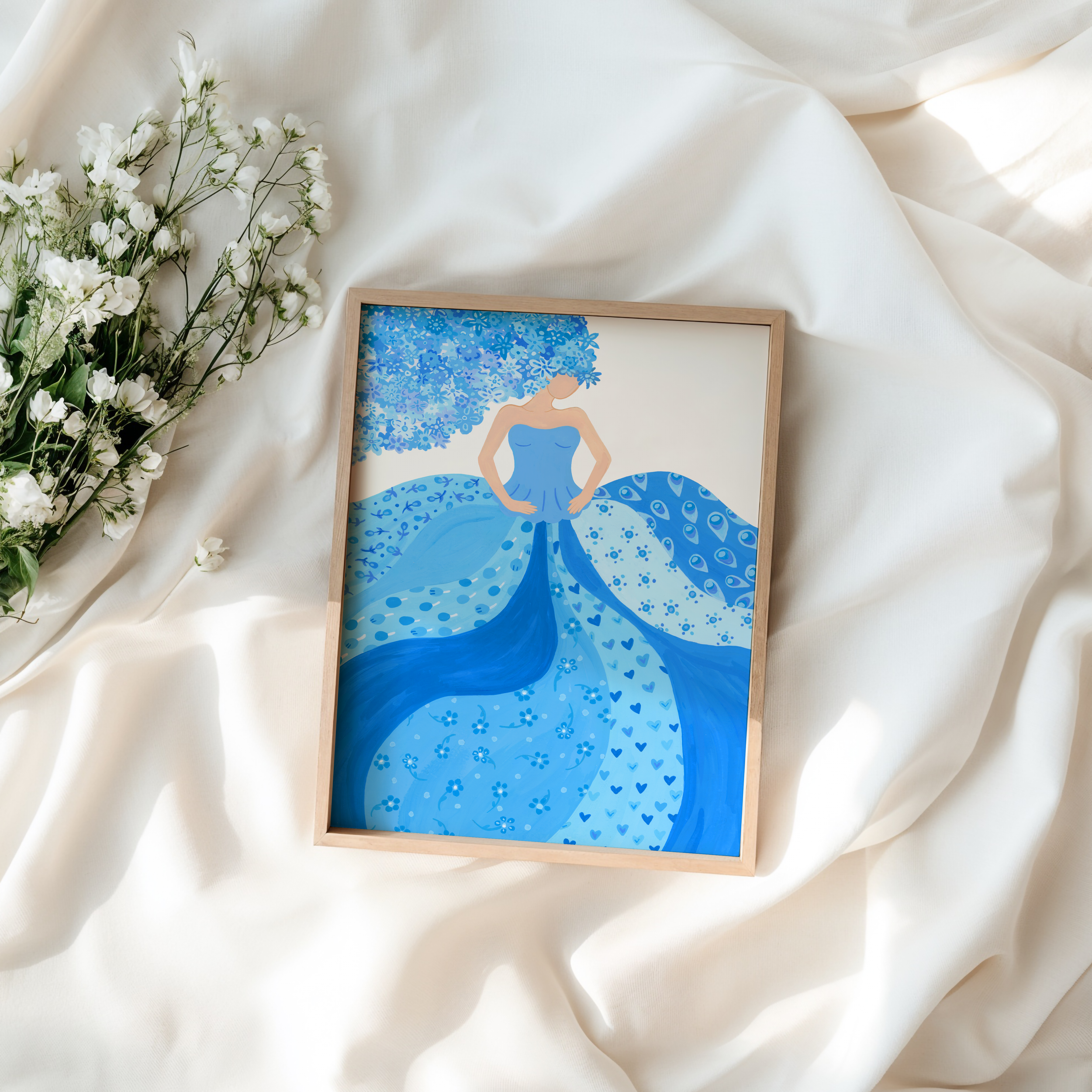 Framed art print of a woman in a blue dress placed on a white bed
