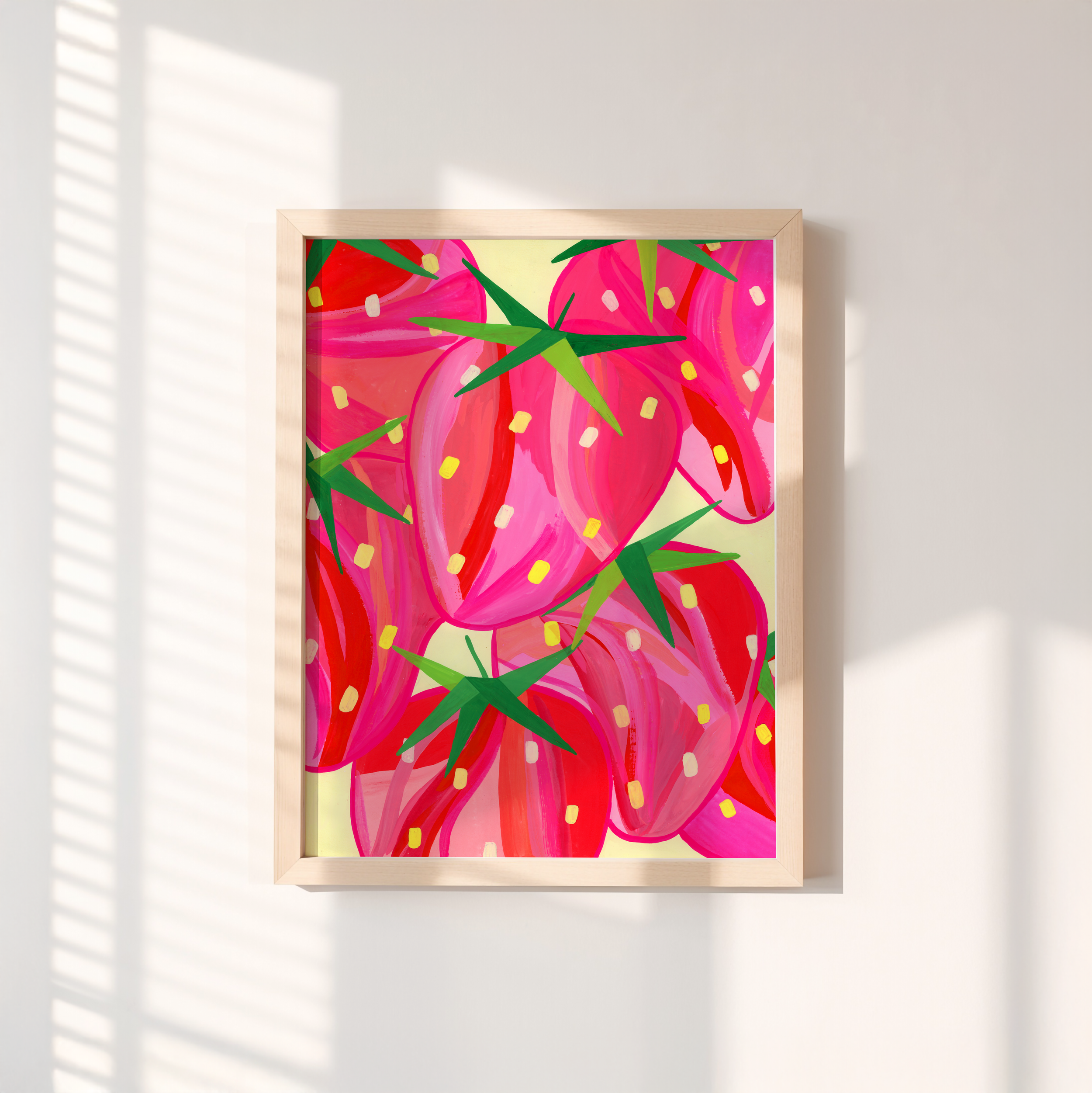 Art print of vibrant abstract strawberries in a wooden frame on a wall with shadows.