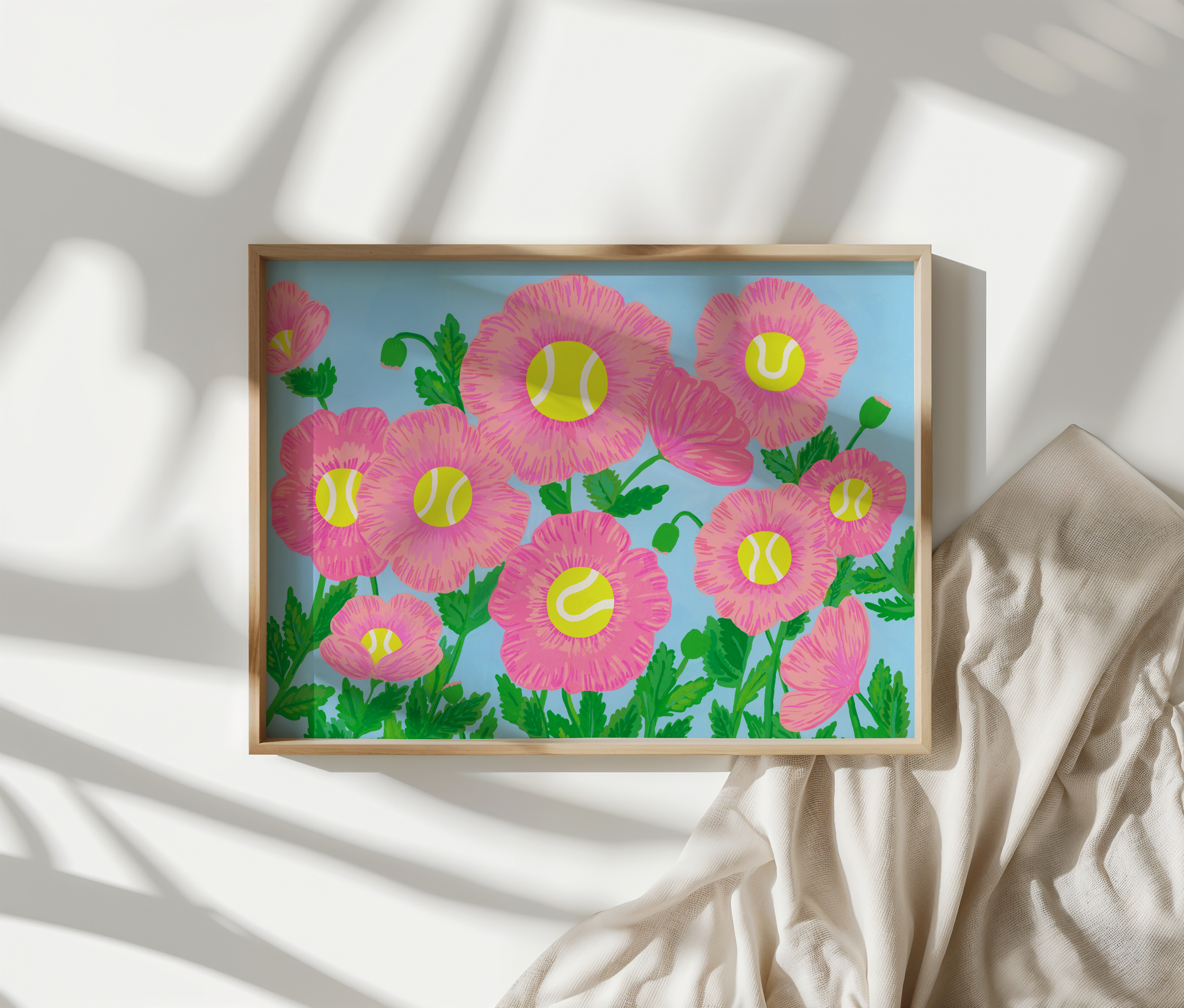 Art print of pink flowers in a wooden frame on a bed with shadows.