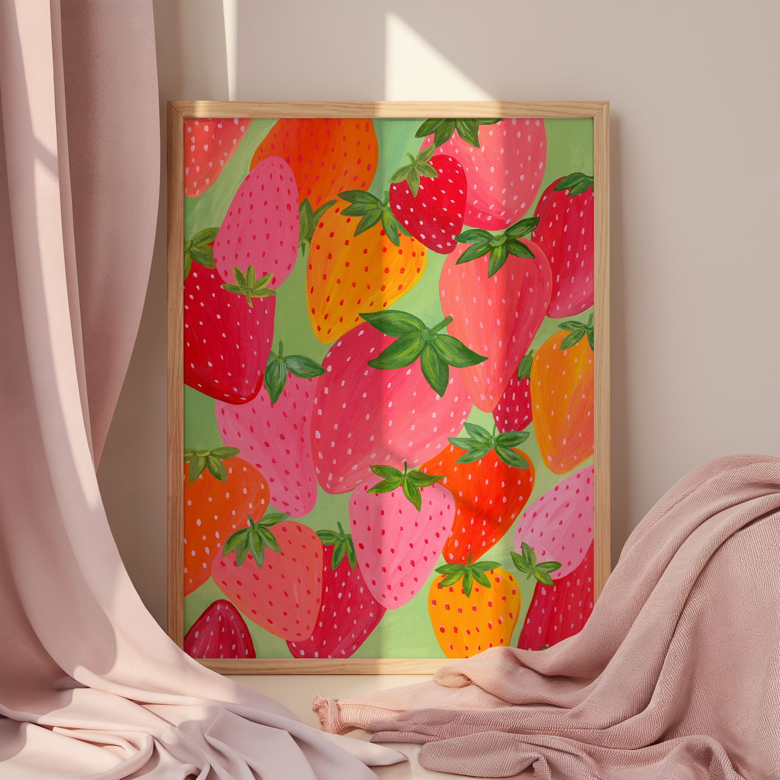 Art print of colorful strawberries in a frame surrounded by pink fabric