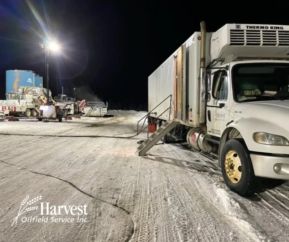 Winter drilling operation at a snowy oilfield site in Western Canada with equipment and service vehicles.