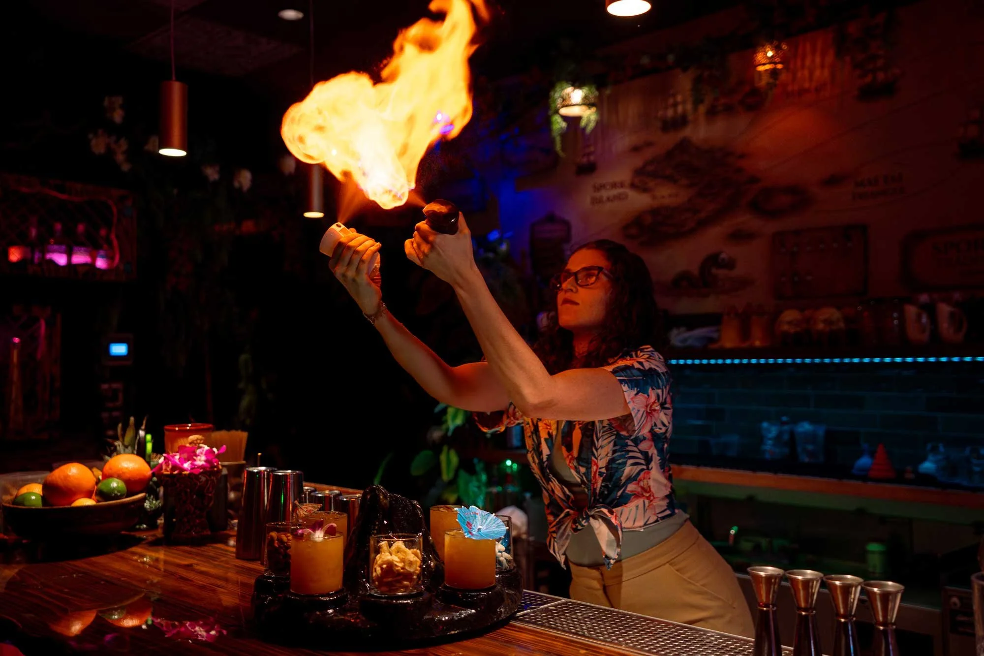 Bartender sends a burst of flame over The Volcano at Spork Island Trading Company, a shared rum cocktail served in eight glasses around a smoking volcano centerpiece, Pittsburgh
