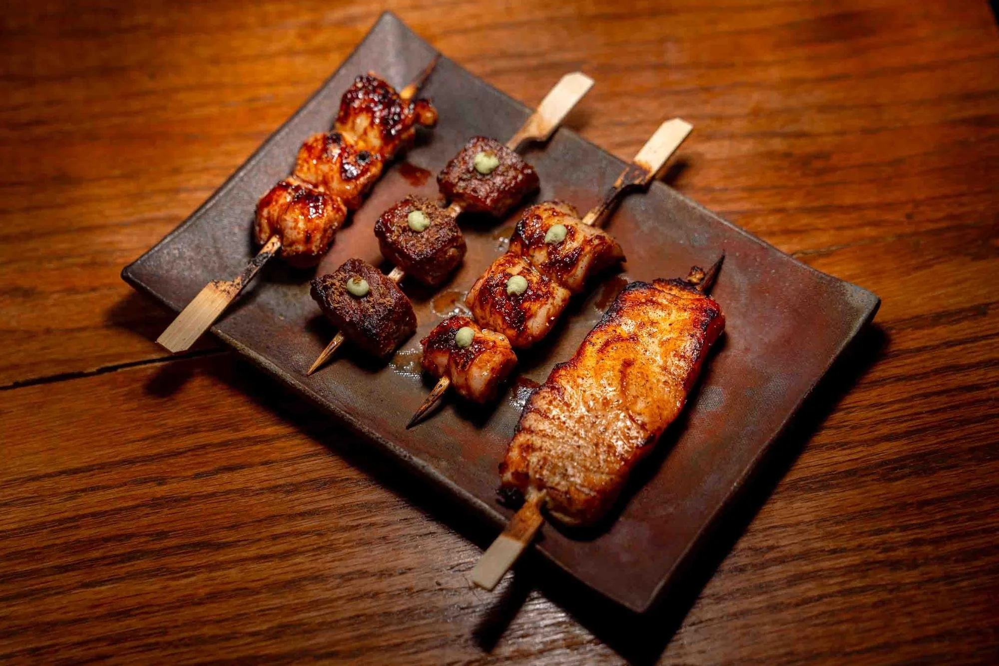Platter of glazed chicken, beef cubes with wasabi and a salmon skewer from the binchotan yakitori grill at Spork Island Trading Company
