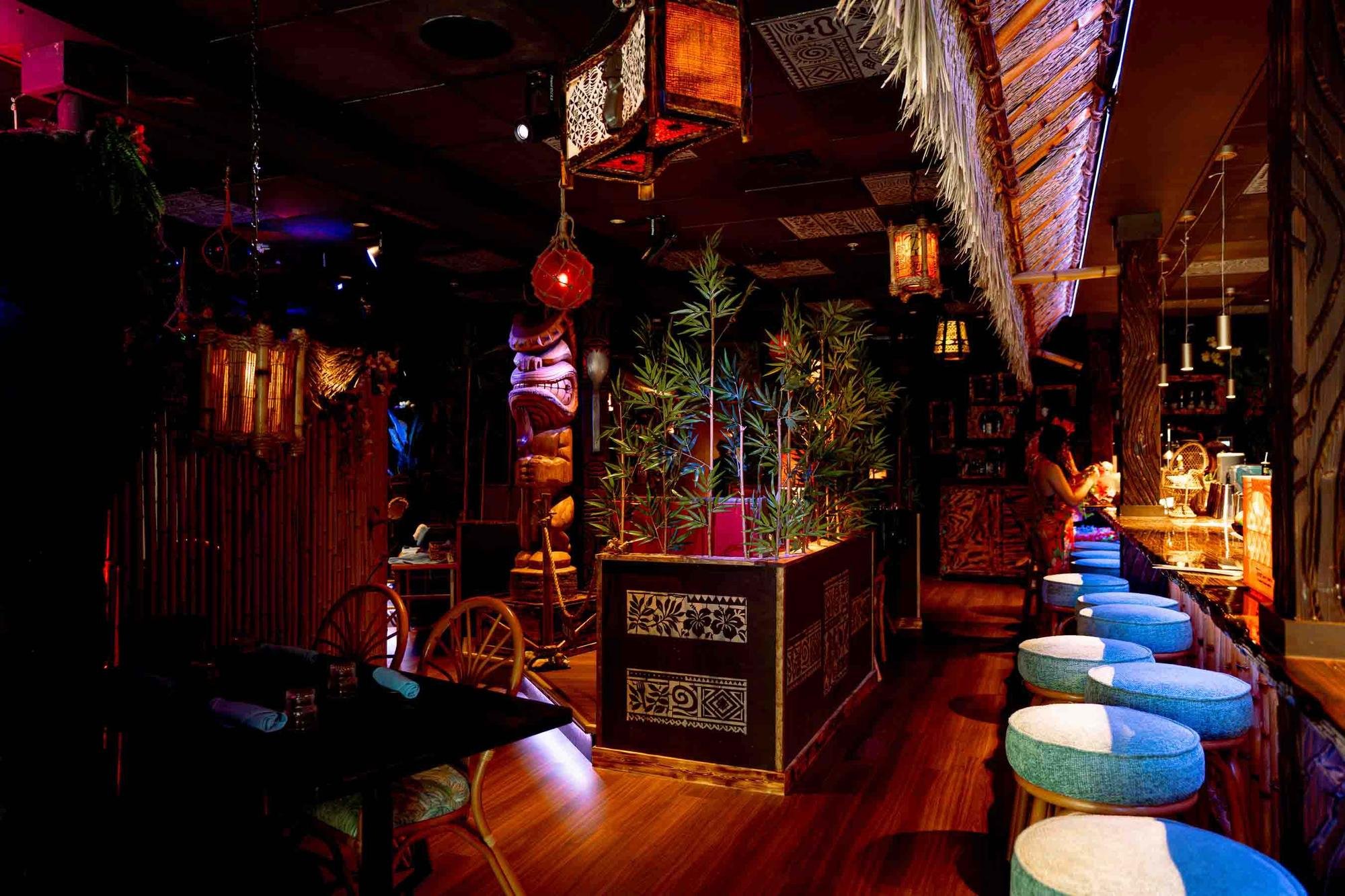 Row of turquoise bar stools along the thatched bar canopy with a bamboo planter and tiki totem at Spork Island Trading Company, downtown Pittsburgh