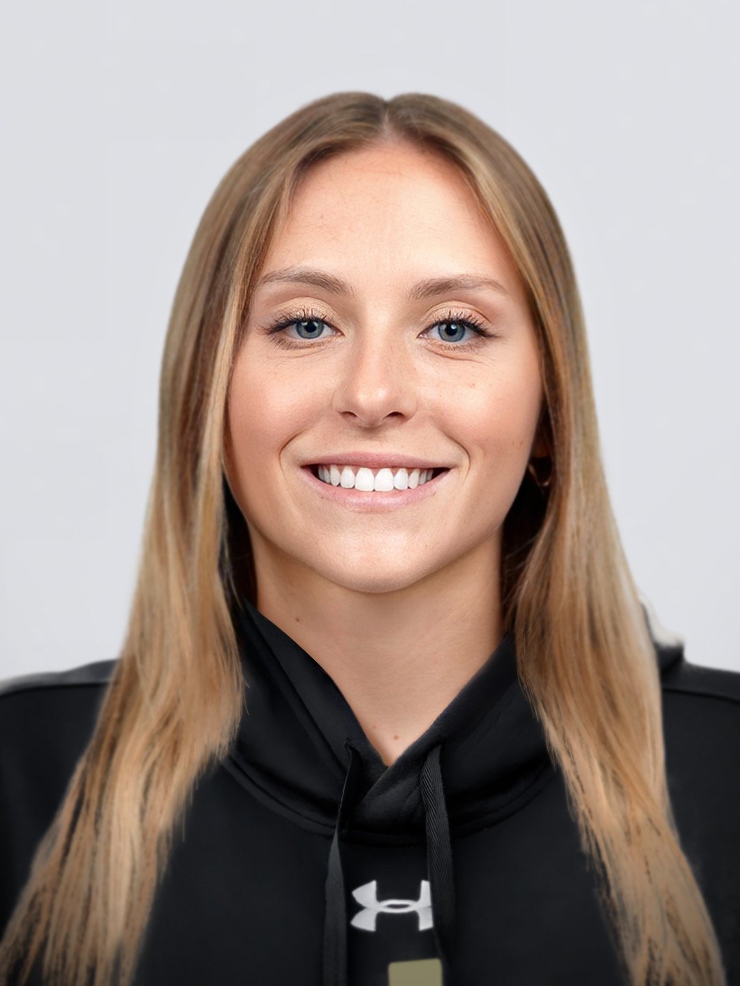 Portrait of a woman smiling, wearing a black hoodie with an Under Armour logo, against a plain background.