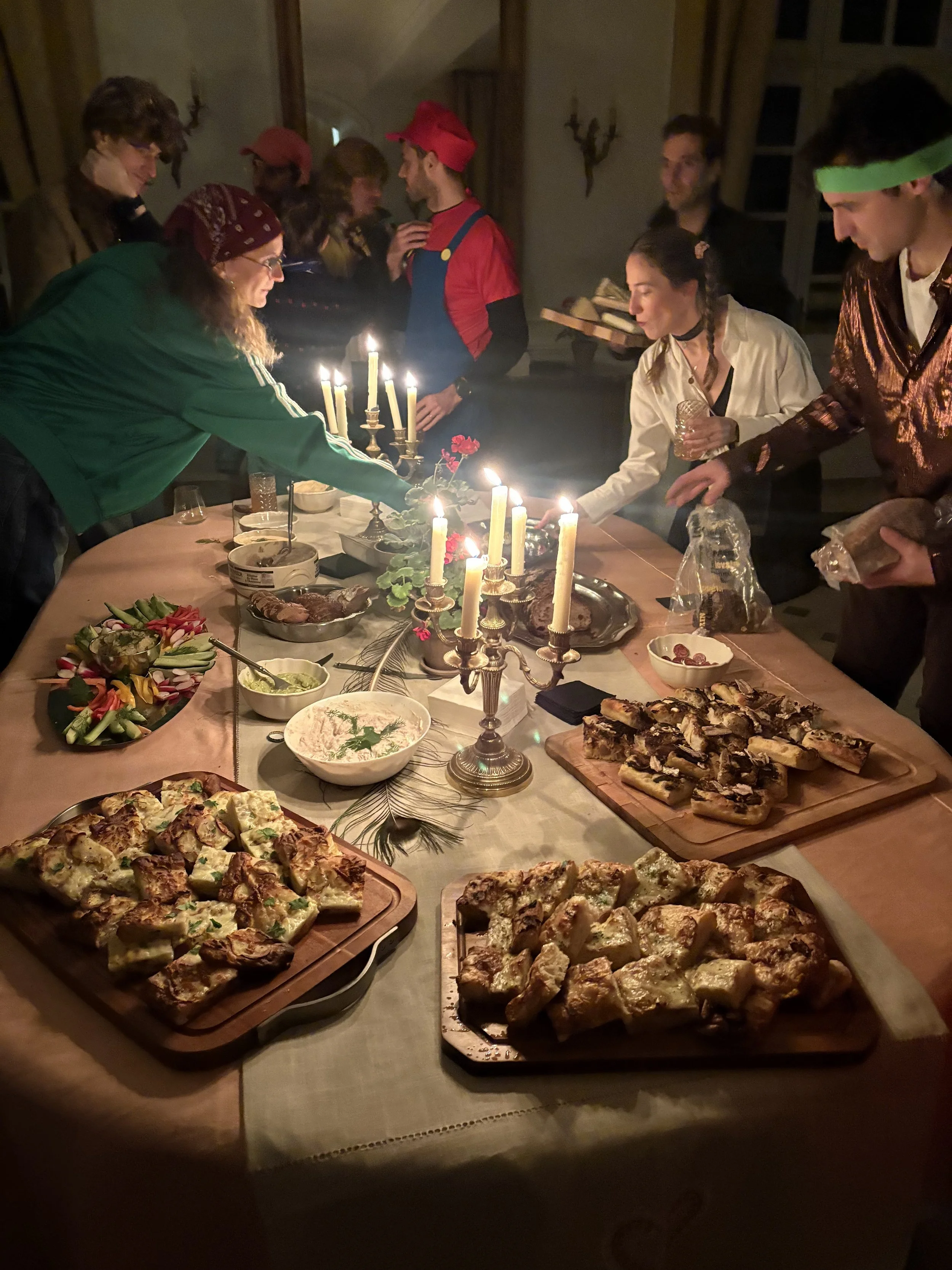 People gathered around a table with food, candles, and decorations, celebrating a festive occasion.