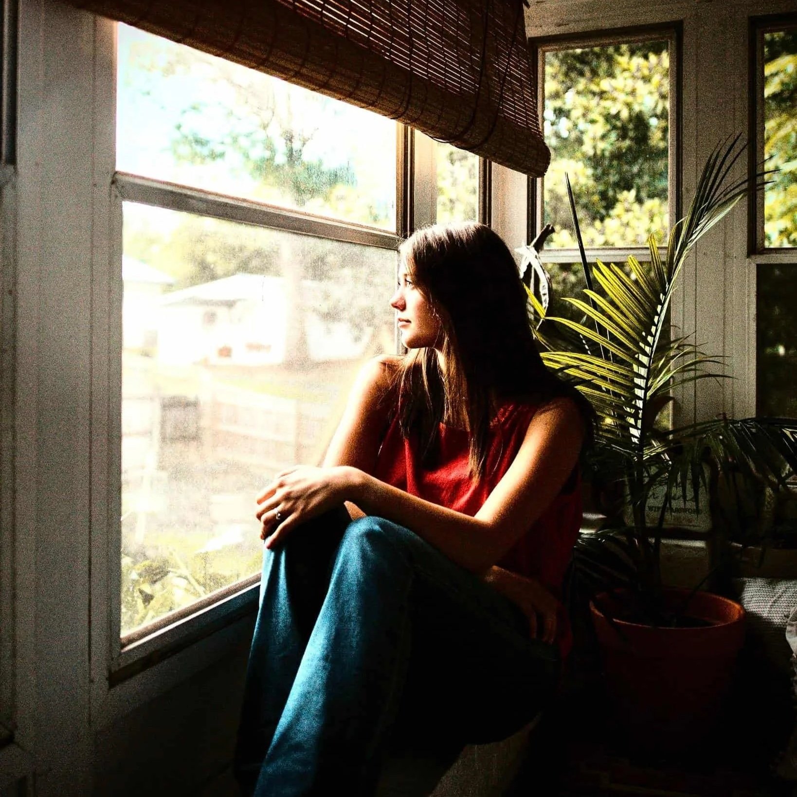 Girl gazing out a blurry window, experiencing mental fog and a longing for clarity.