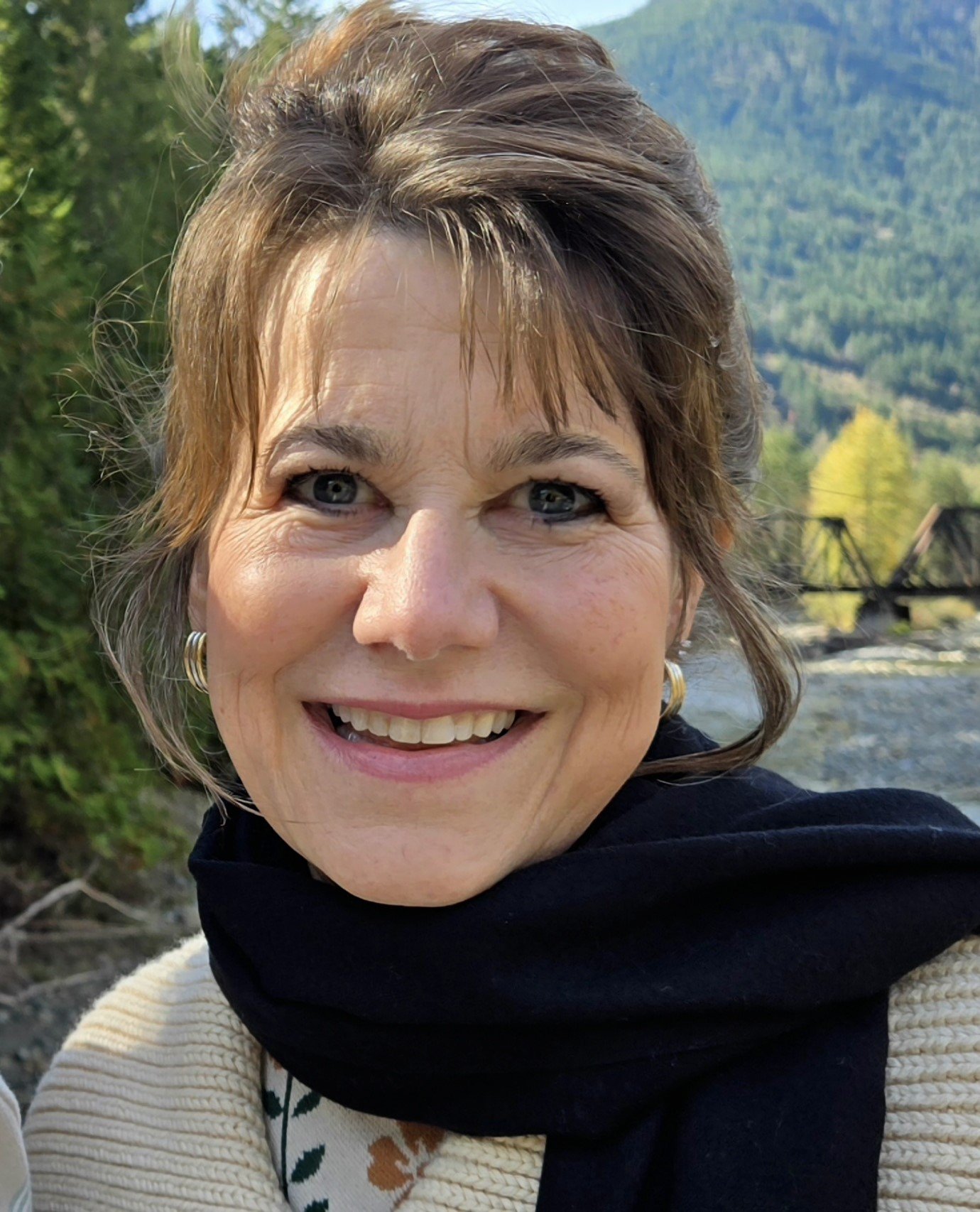 Suzette Parker, board-certified life coach and creator of UNAFRAID Living, smiling outdoors with mountains behind her.