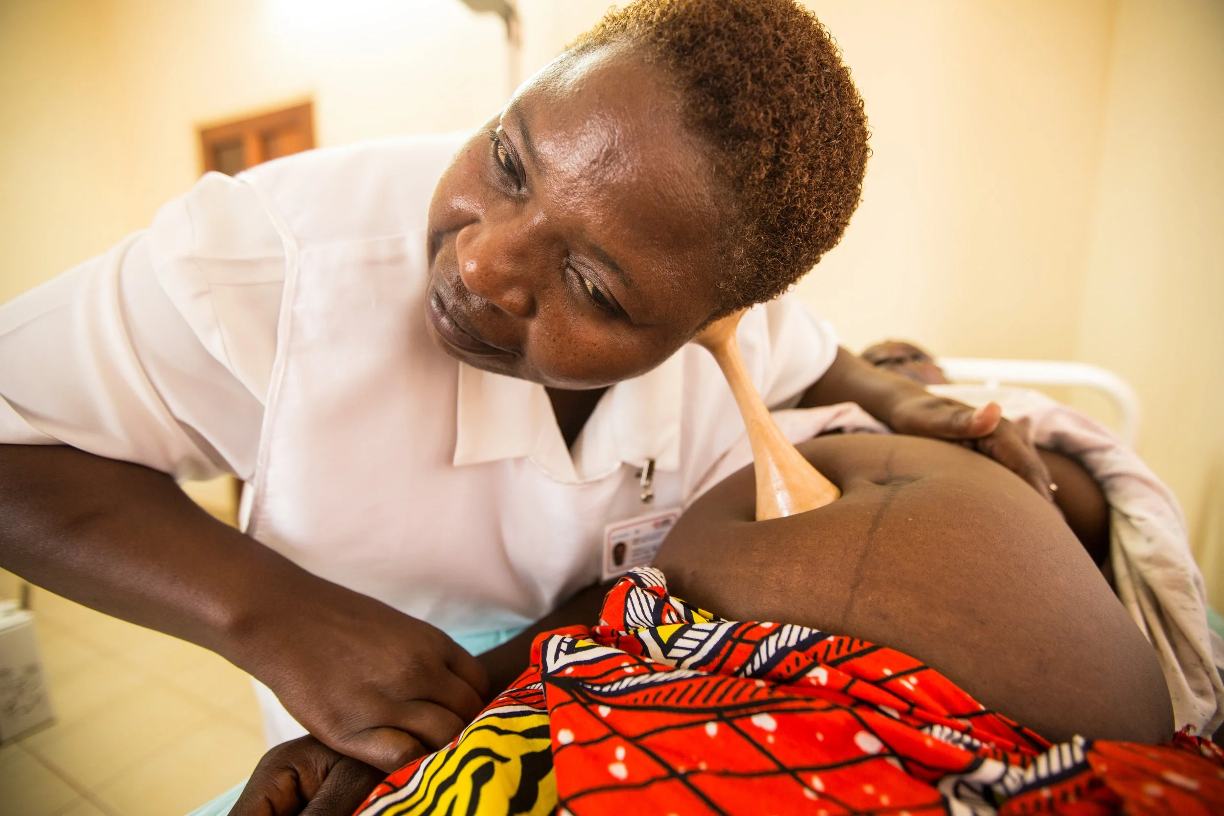 A healthcare professional performing an abdominal ultrasound on a patient in a hospital room.
