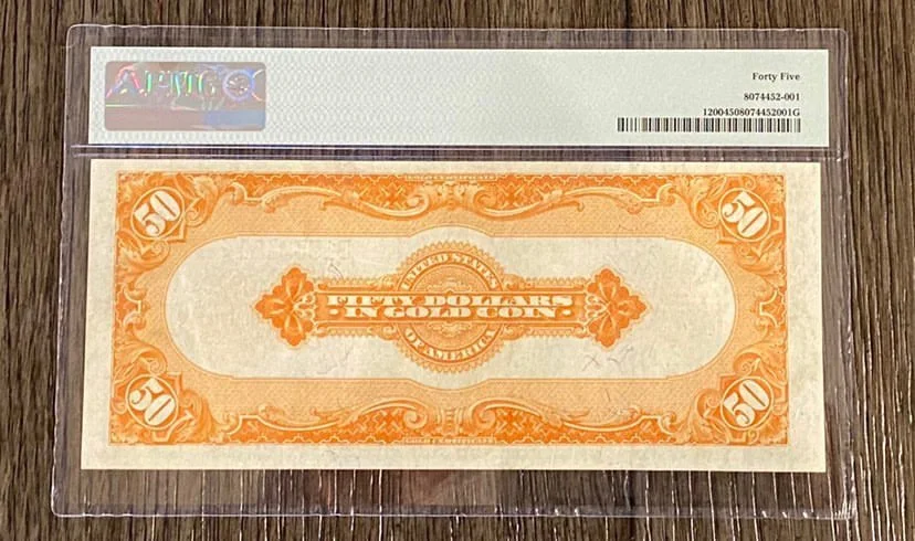 A 50-dollar bill in a clear plastic sleeve on a wooden surface.