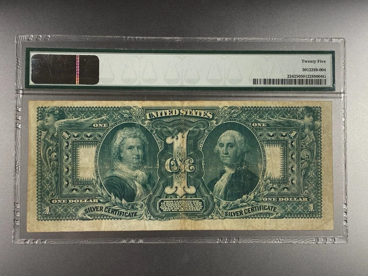 A one-dollar silver certificate bill encased in a plastic holder with a grading label at the top.