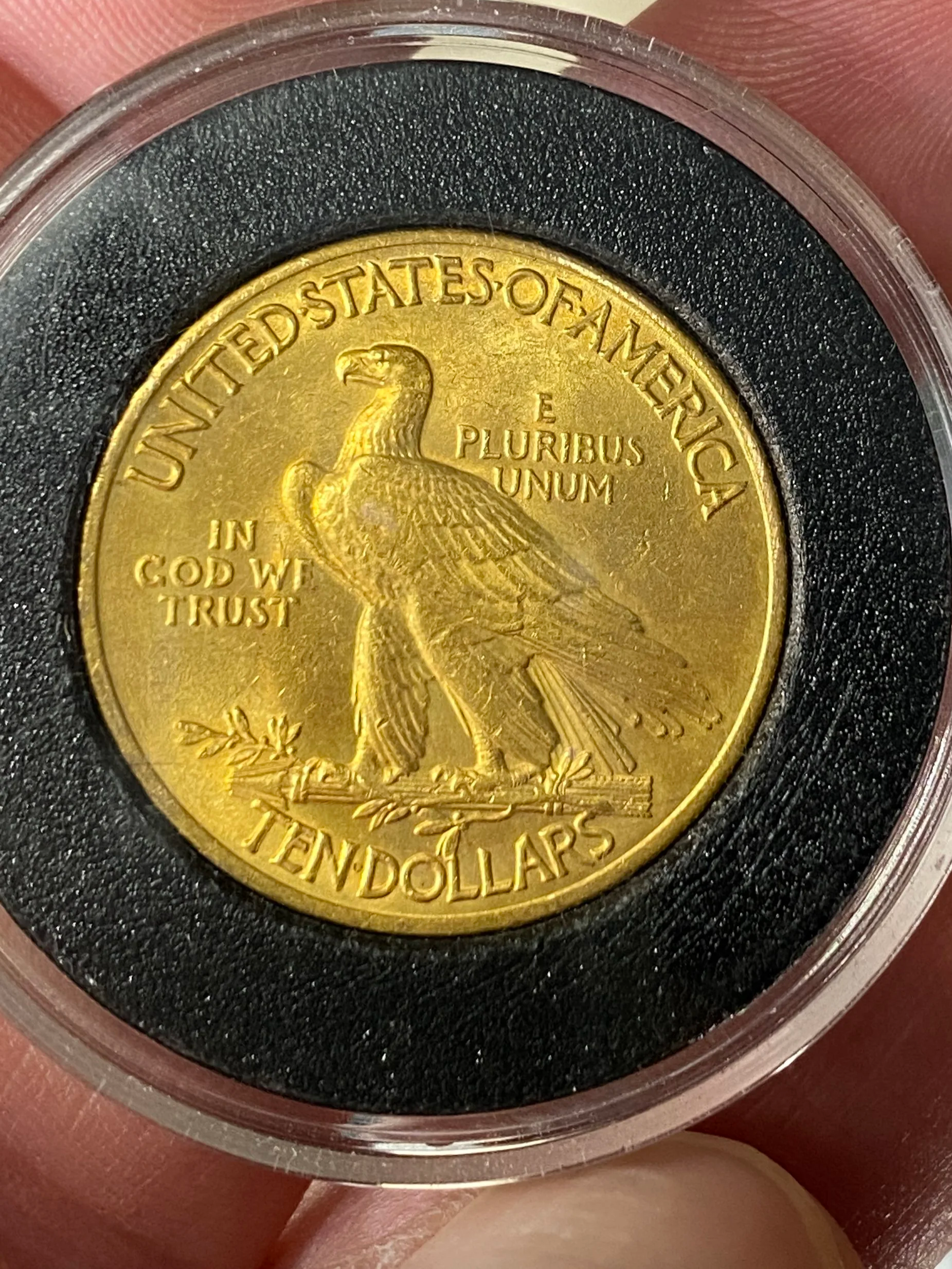 A gold-colored United States quarter featuring an eagle on the reverse side, with inscriptions including 'United States of America', 'E Pluribus Unum', 'In God We Trust', and the denomination 'Ten Dollars'.