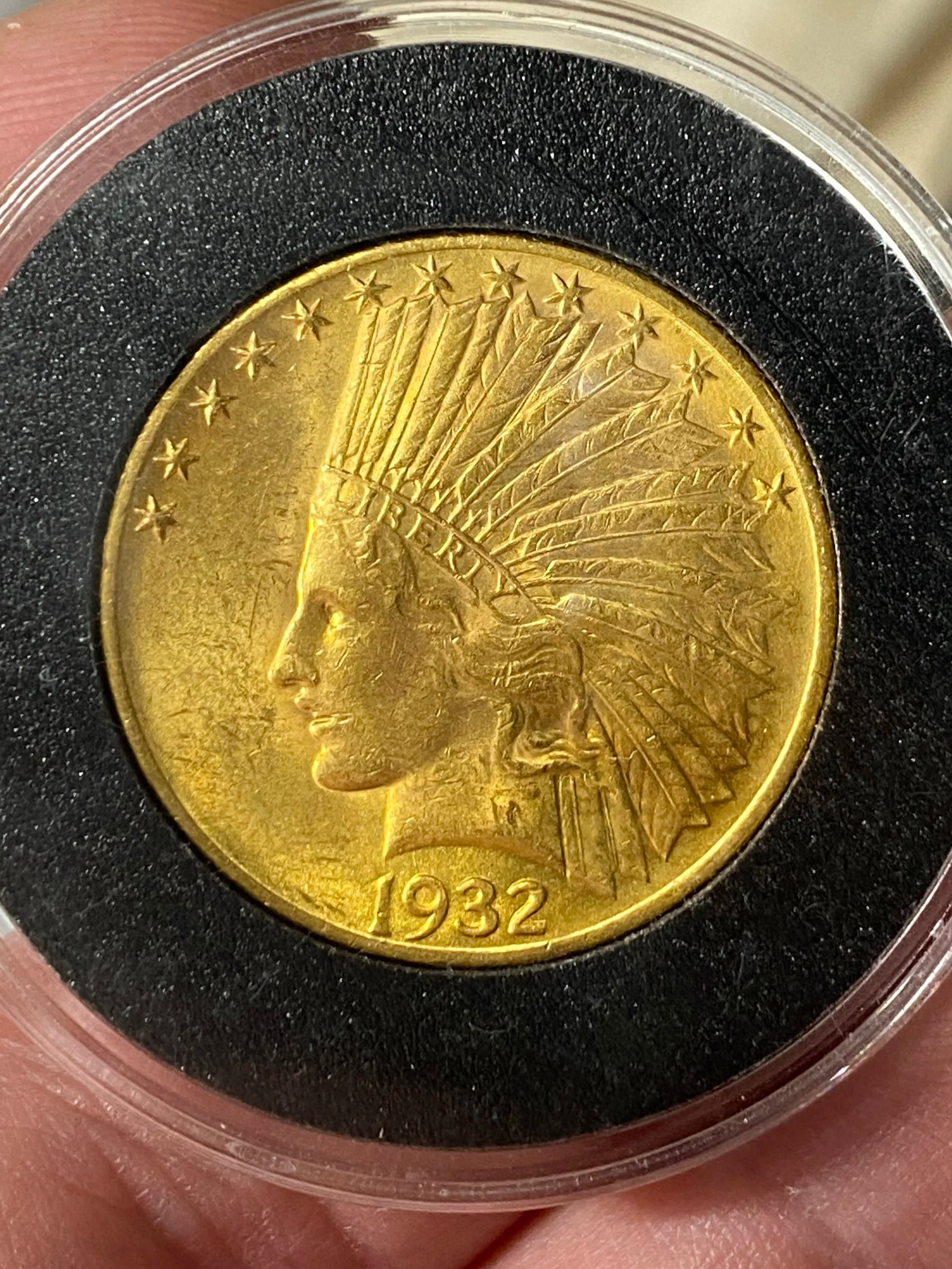 A 1932 American gold coin featuring a Native American woman wearing a feathered headdress, encased in a protective holder.