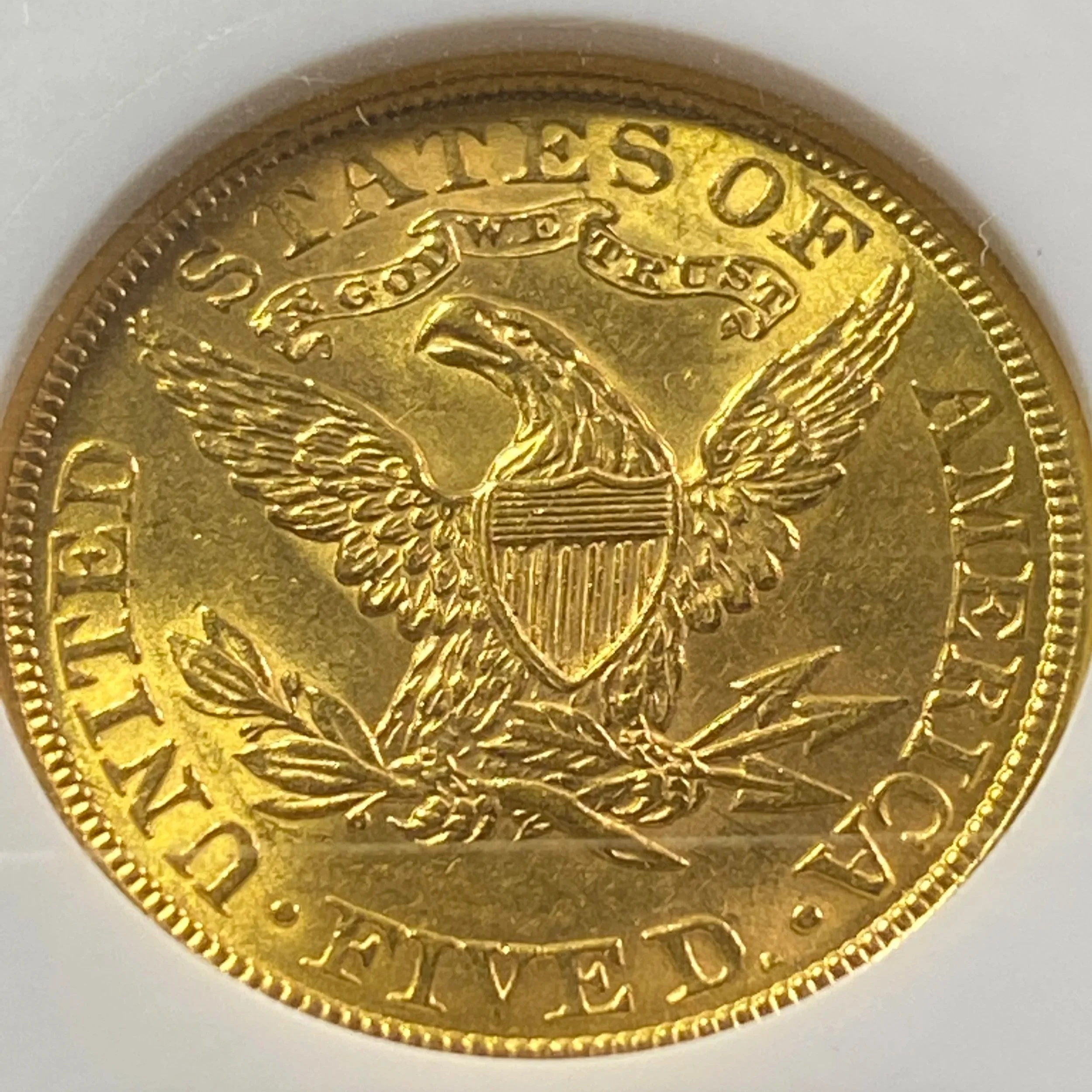 Close-up of a gold coin with an eagle holding arrows and an olive branch.
