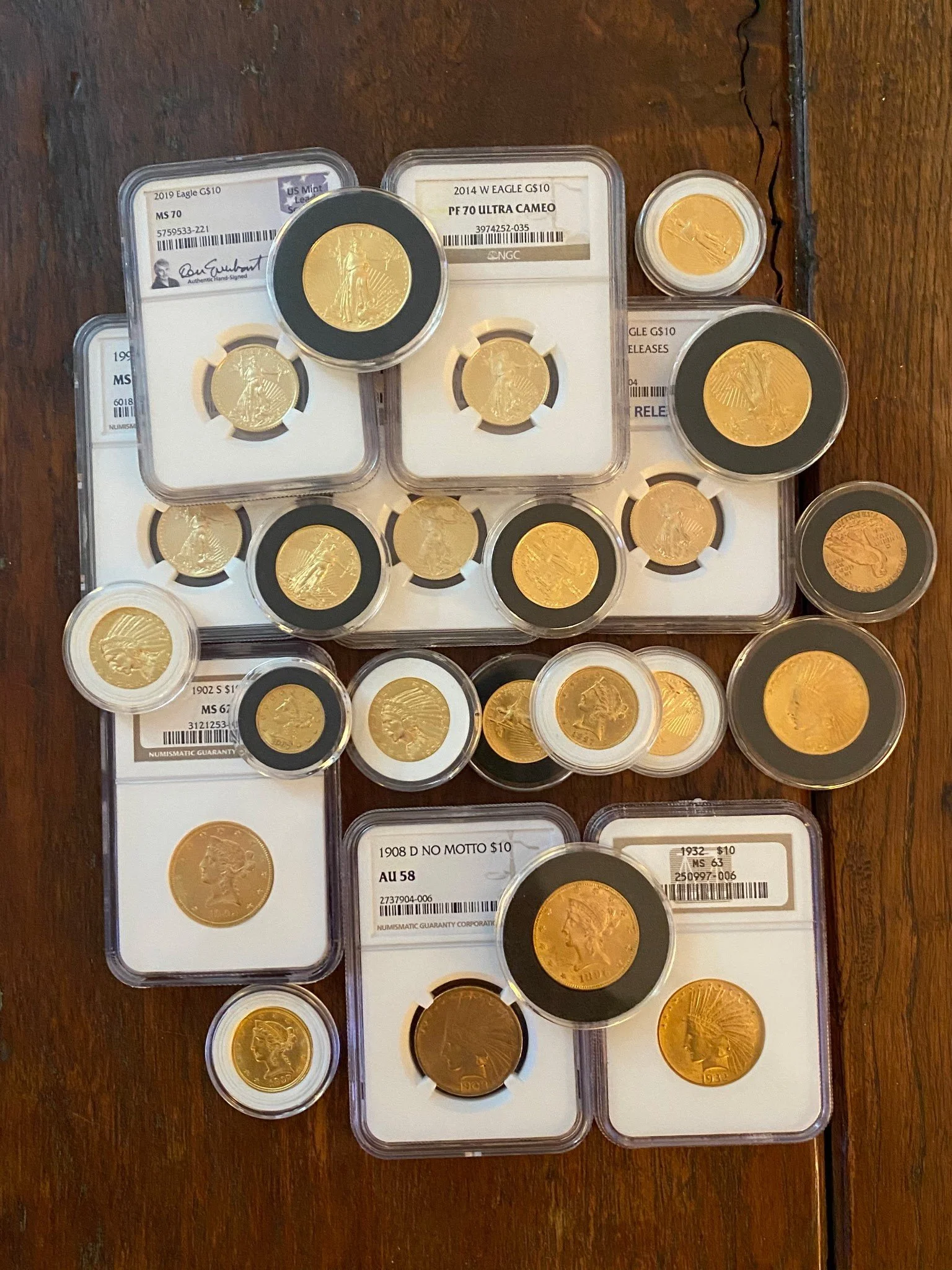A collection of gold coins in protective casings, displayed on a wooden surface.