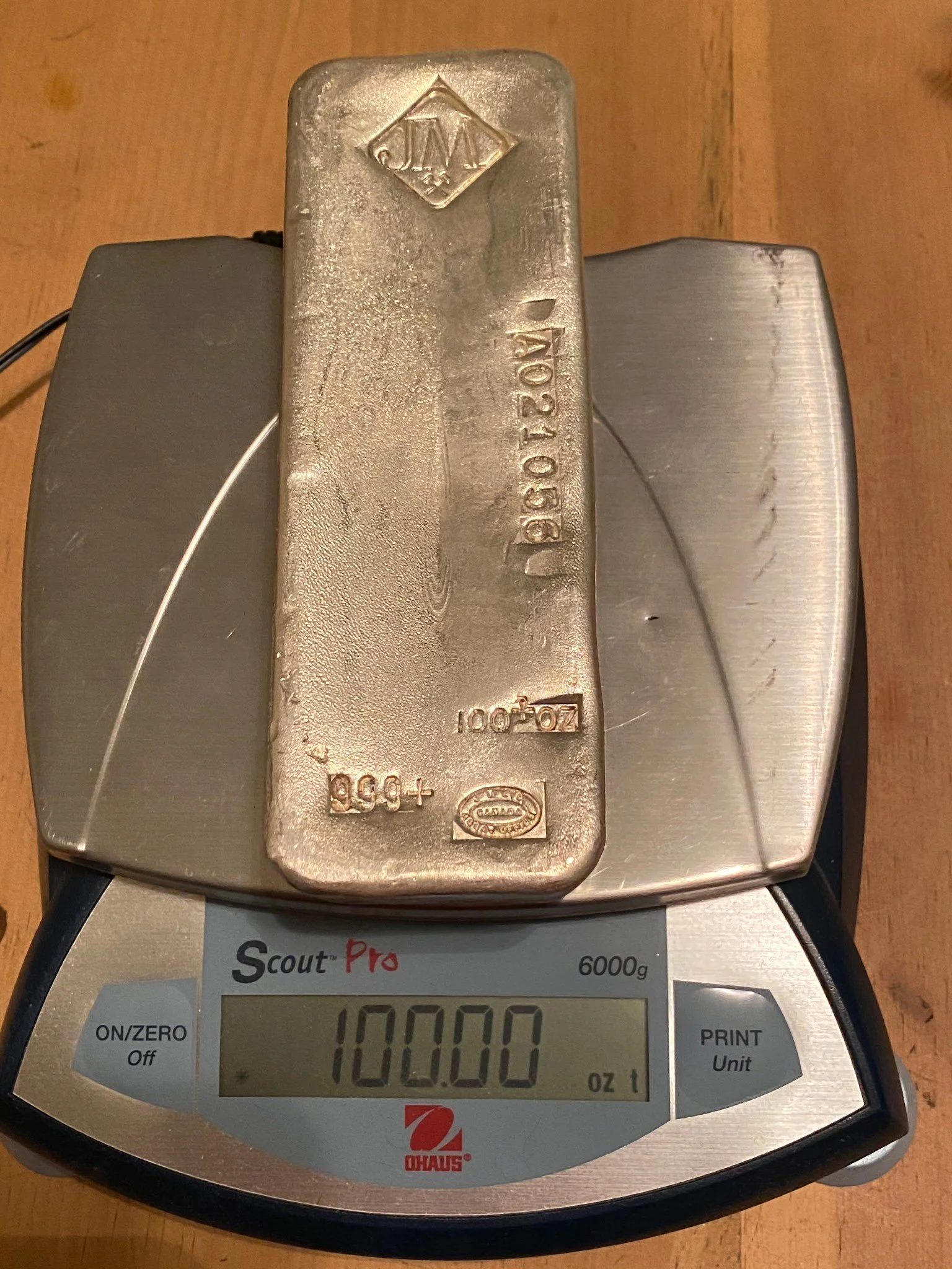 A silver metal bar weighing 10,000 ounces on a digital scale.