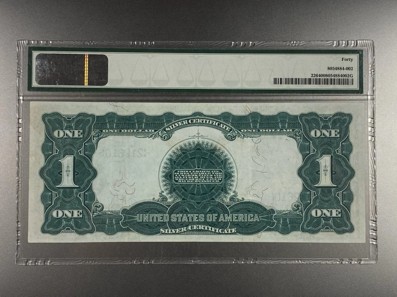 A one-dollar bill encased in a clear protective plastic holder with a certification label at the top.