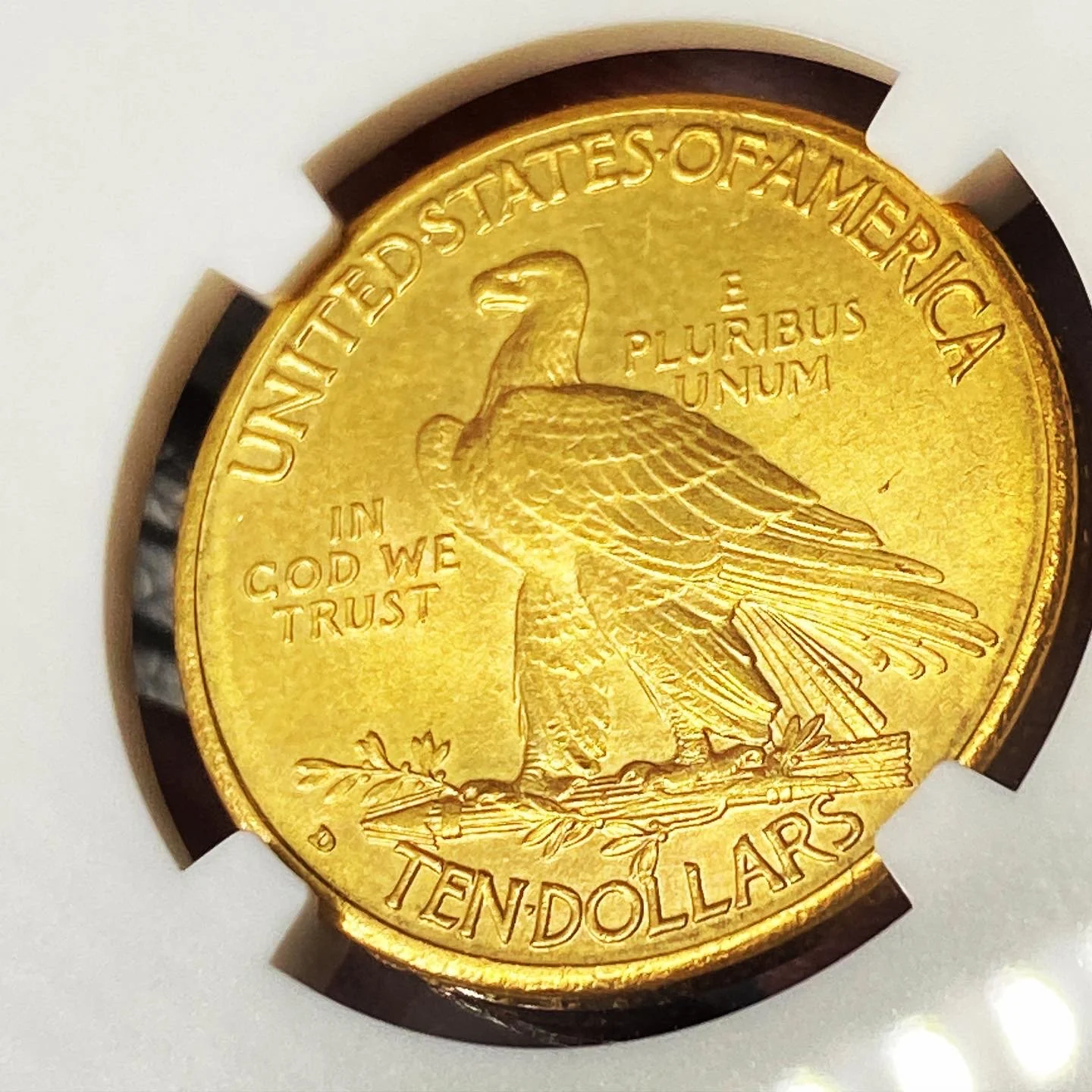 Close-up of a U.S. ten-dollar gold coin featuring an eagle with outstretched wings, facing left, with the inscriptions 'United States of America,' 'E Pluribus Unum,' 'In God We Trust,' and 'Ten Dollars.'