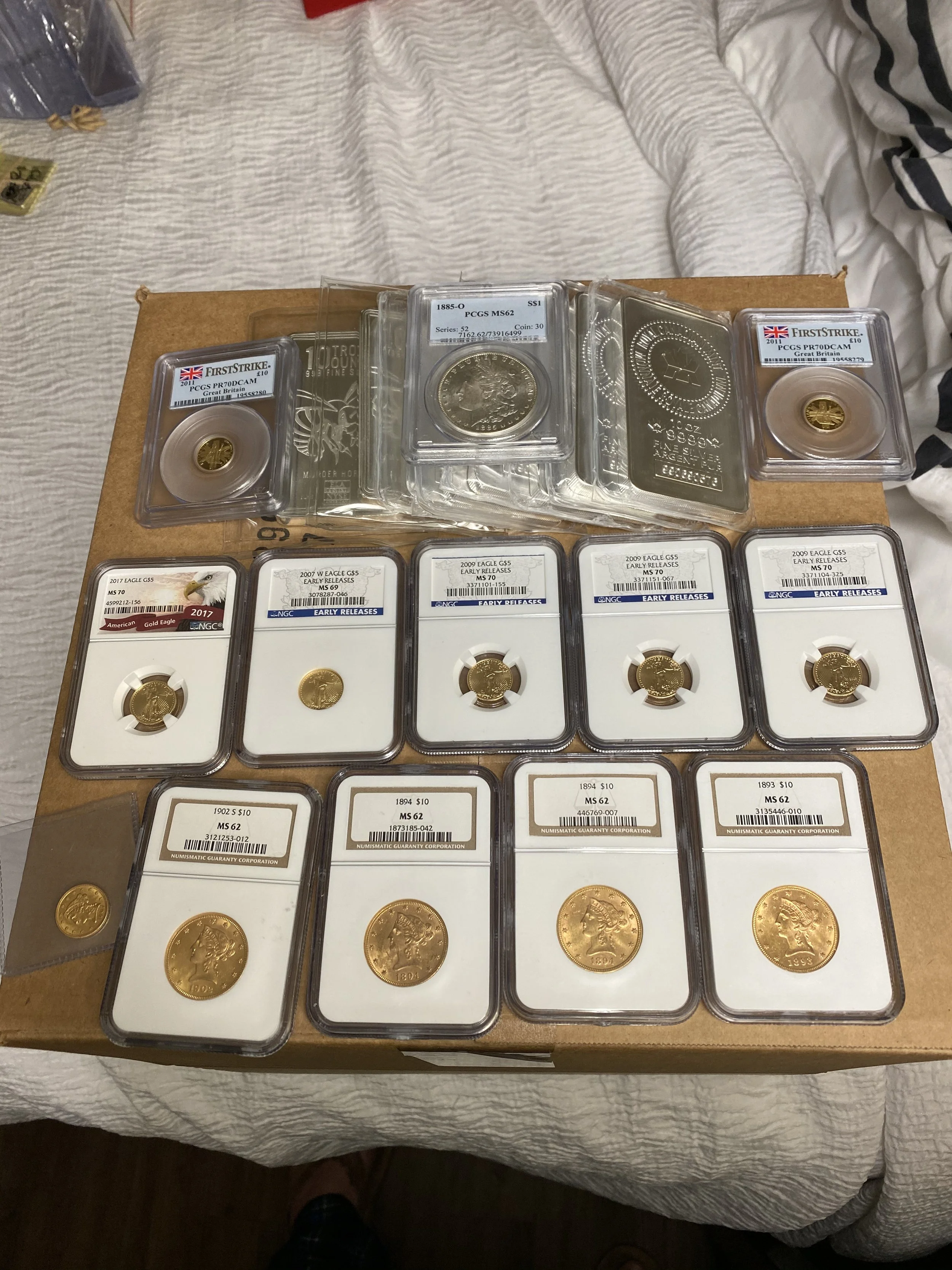 Collection of graded and ungraded coins, including gold coins, displayed on a table.