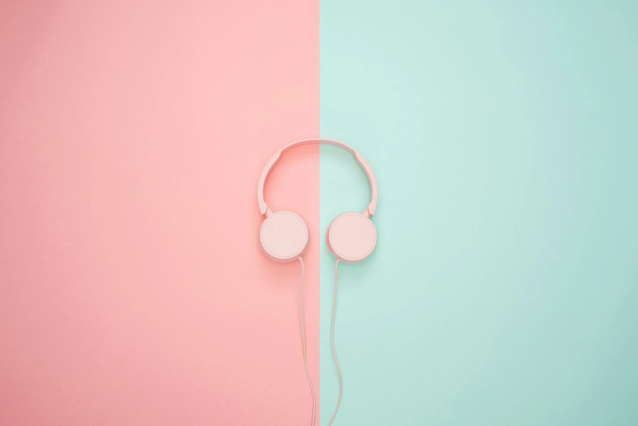 Pink headphones on a background split into pink and mint green halves.