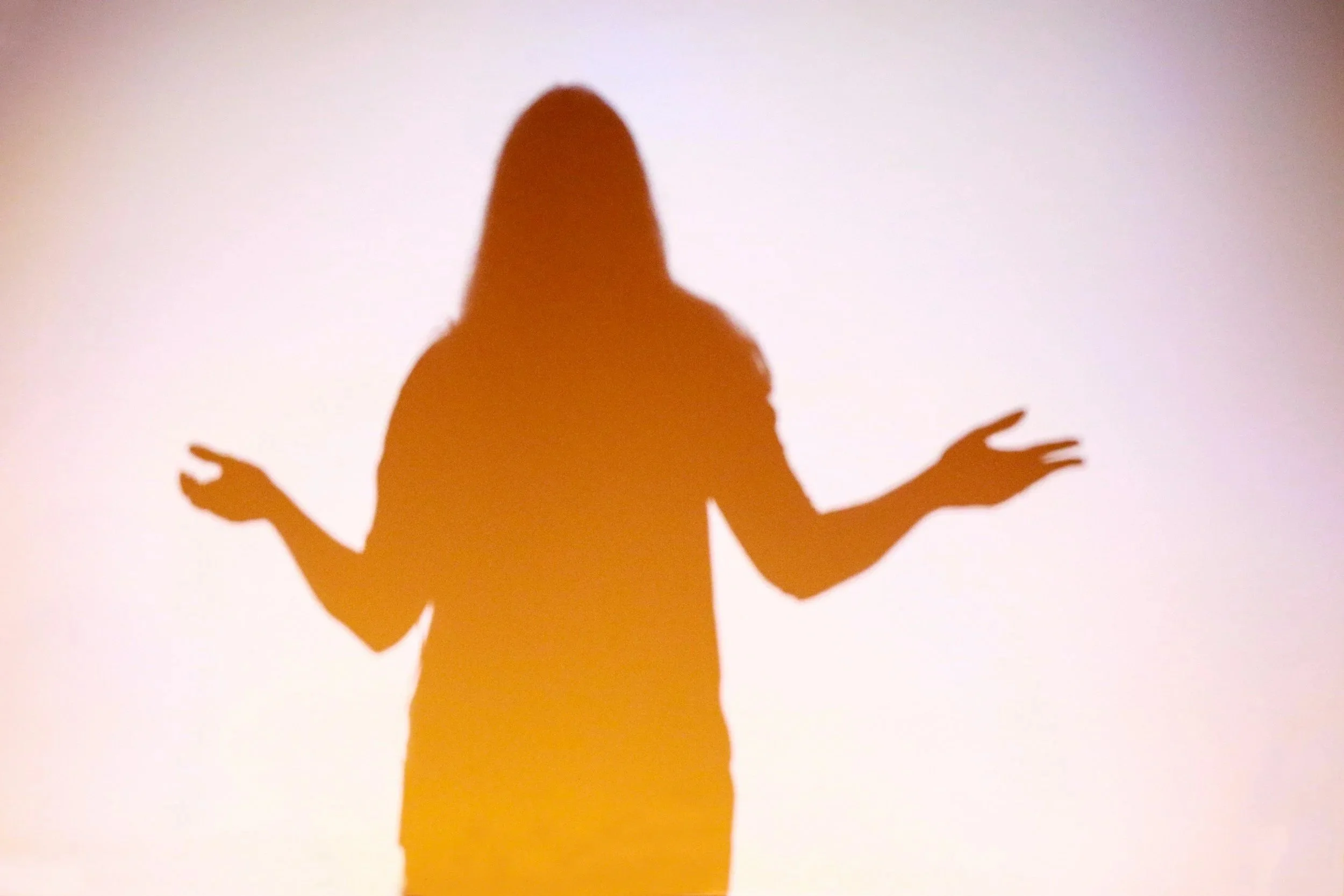 Silhouette of a woman with her arms raised and palms open, against a light background.