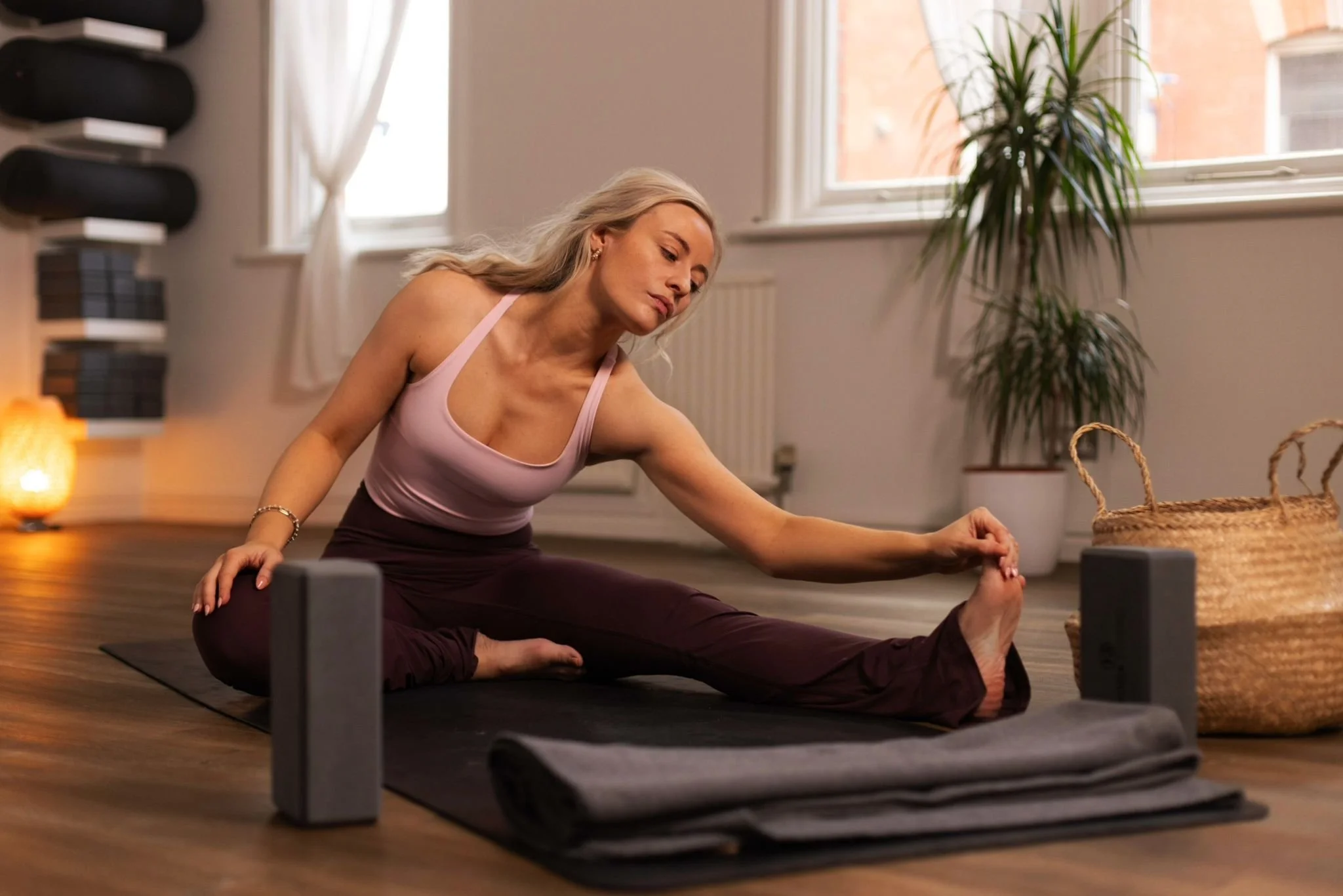 Girl stretches on yoga mat with one leg outstretched